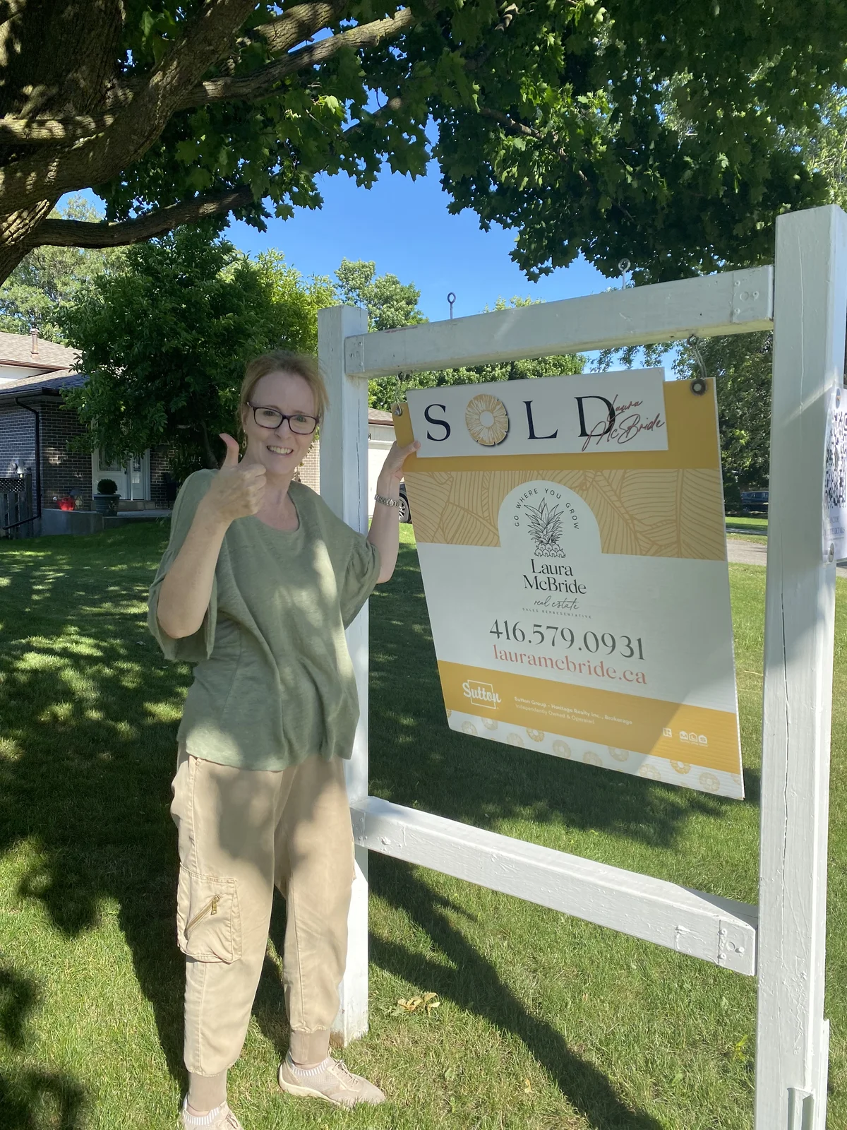 An Ajax seller celebrating a SOLD sign with Laura McBride while relocating to Port Hope