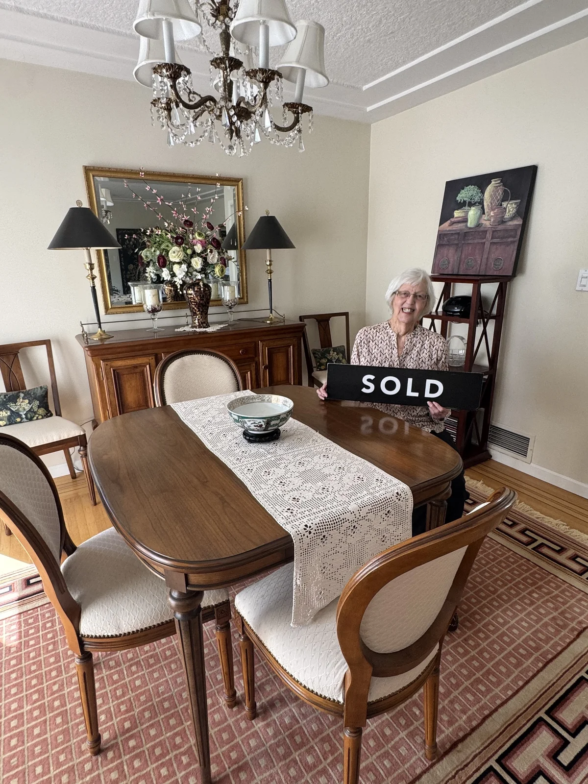 A client's aunt in Vancouver celebrating with a SOLD sign after downsizing her 40-year home before relocating to Durham Region