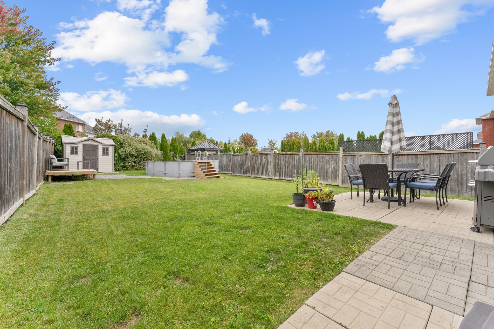 Fully fenced backyard at 1683 Finkle Drive, Oshawa, with a spacious patio, above-ground pool and shed
