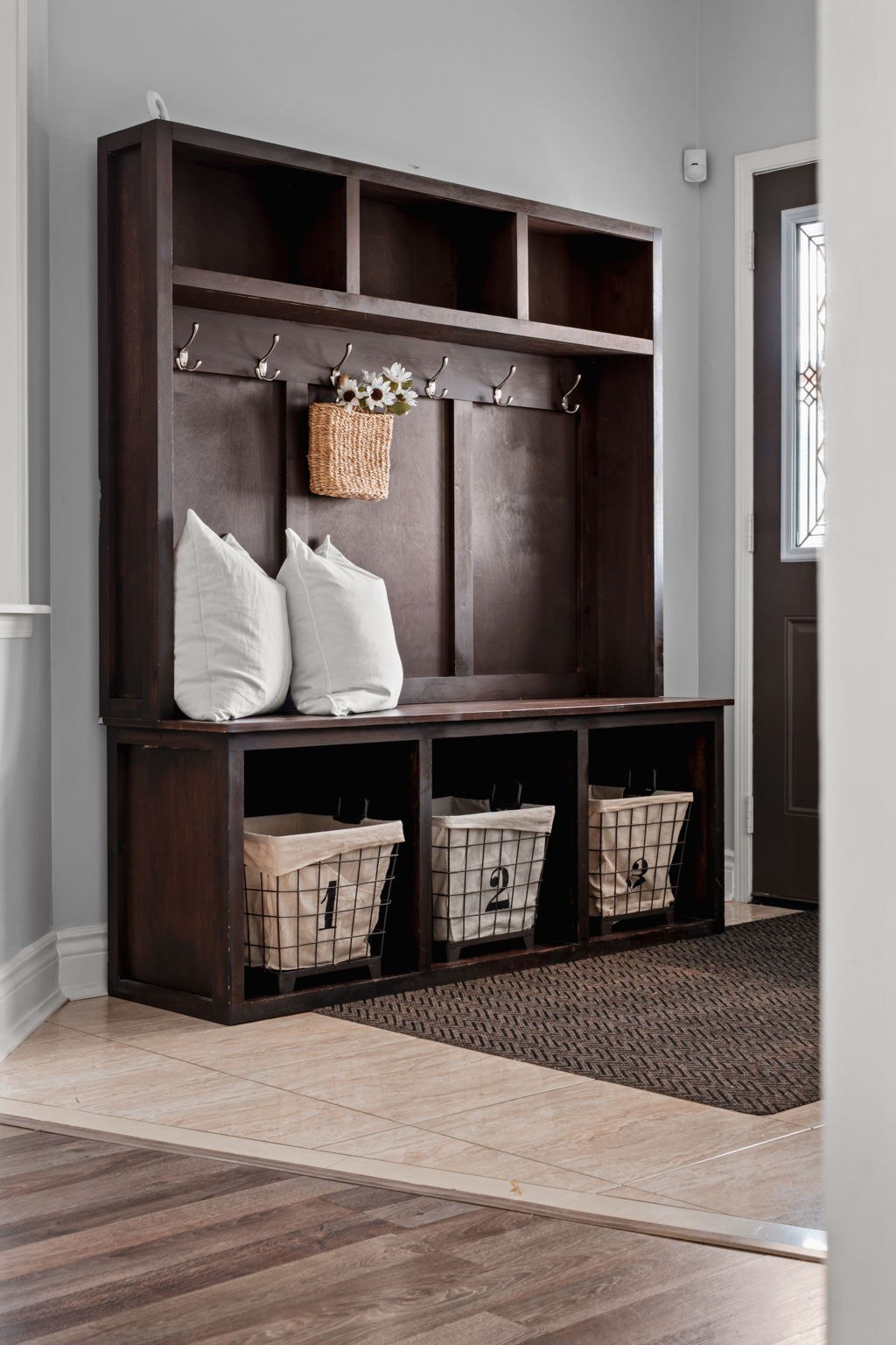 Foyer bench styling detail at 1683 Finkle Drive, Oshawa, with layered pillows and woven storage baskets