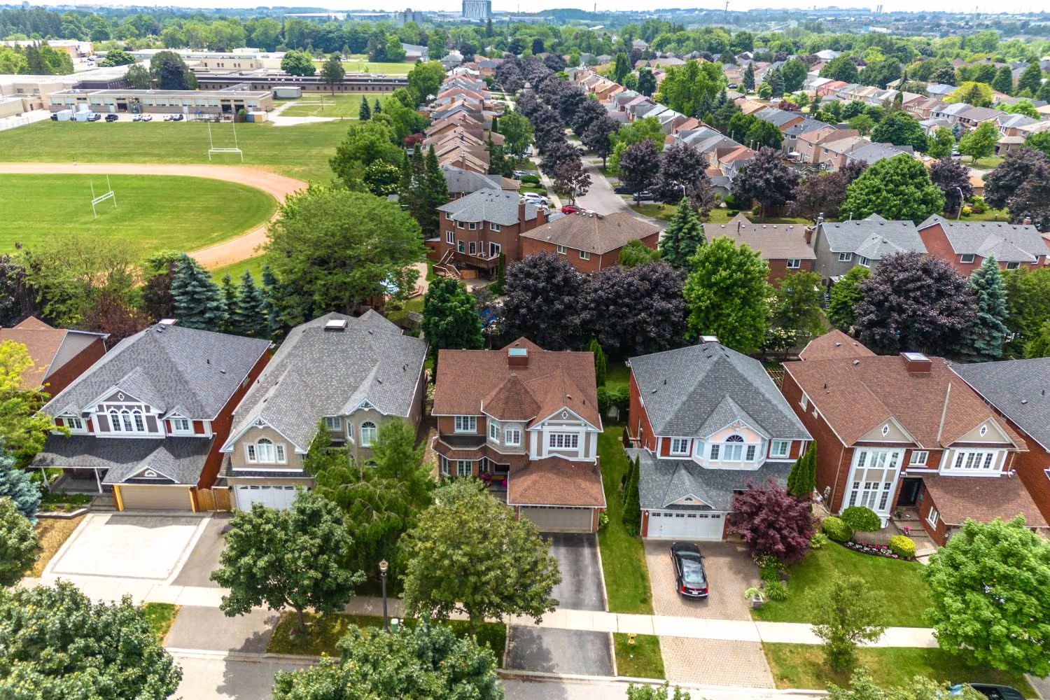 Aerial view of a Riverside Ajax neighbourhood, detached homes on mature, tree-lined streets near a school