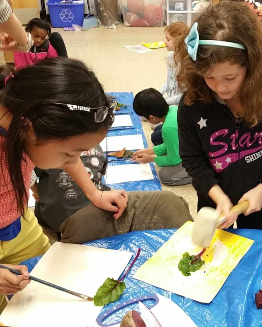 Students using beet greens from their classroom garden to create art by painting with the natural juice from the leaves
