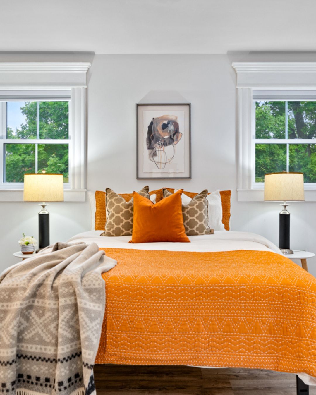 Primary bedroom after staging with warm orange bedding, layered pillows, and natural light creating a fresh and inviting space