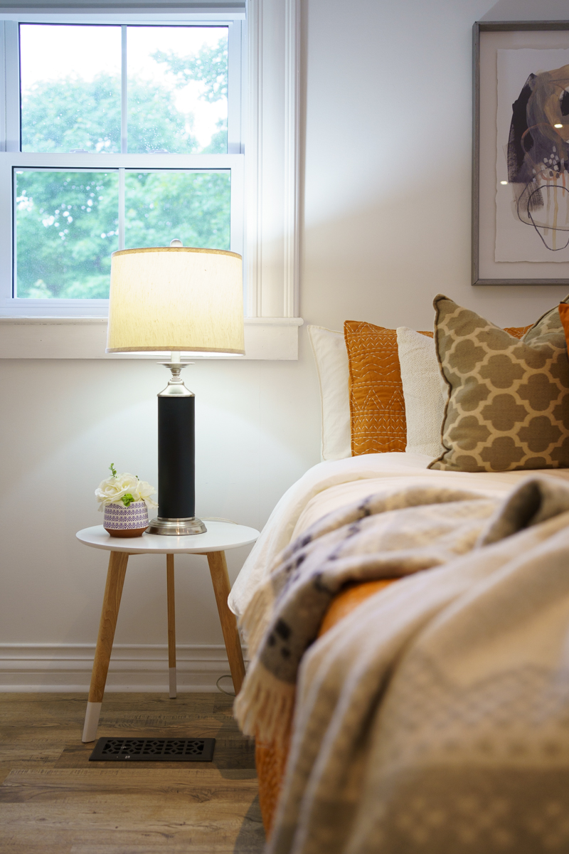 Primary bedroom after staging showing a bright, cozy corner with layered pillows, warm lighting, and magazine-quality presentation