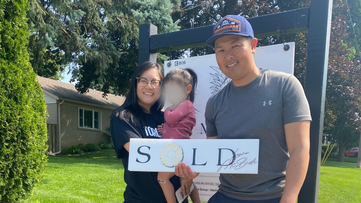 Proud Pickering Village sellers standing beside their SOLD sign after working with Laura McBride.