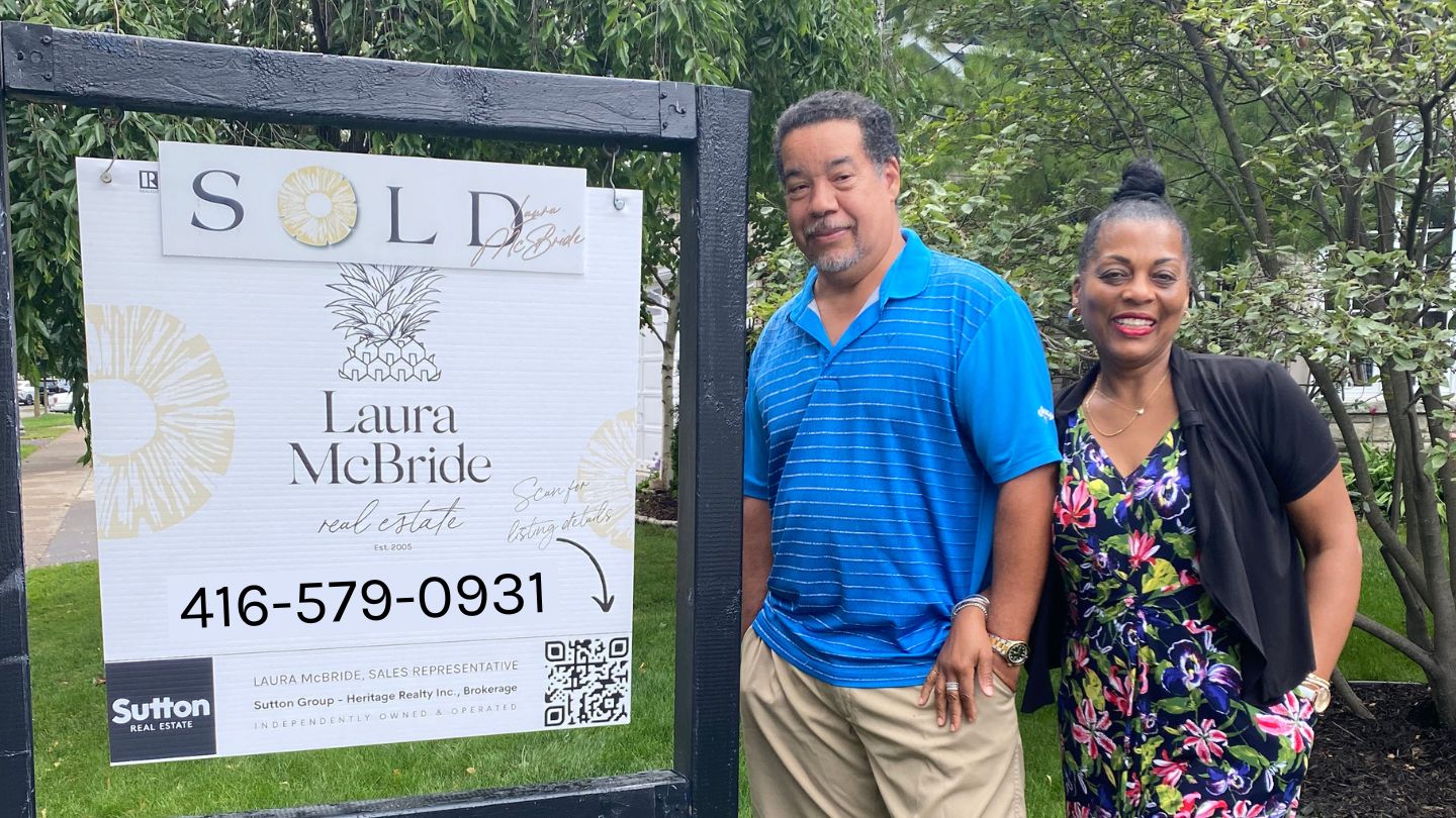 Proud Pickering Village sellers standing beside their SOLD sign after working with Laura McBride.