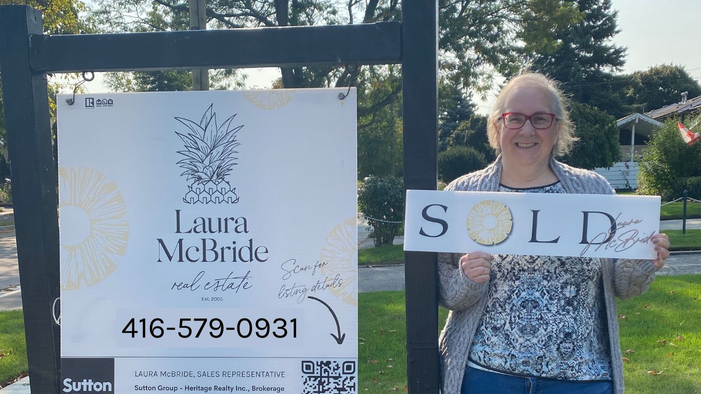 Smiling seller standing beside a SOLD sign on their Scarborough property with Laura McBride branding.