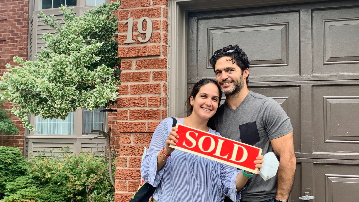 Happy sellers holding a SOLD sign in front of their South Ajax home sold by Laura McBride.