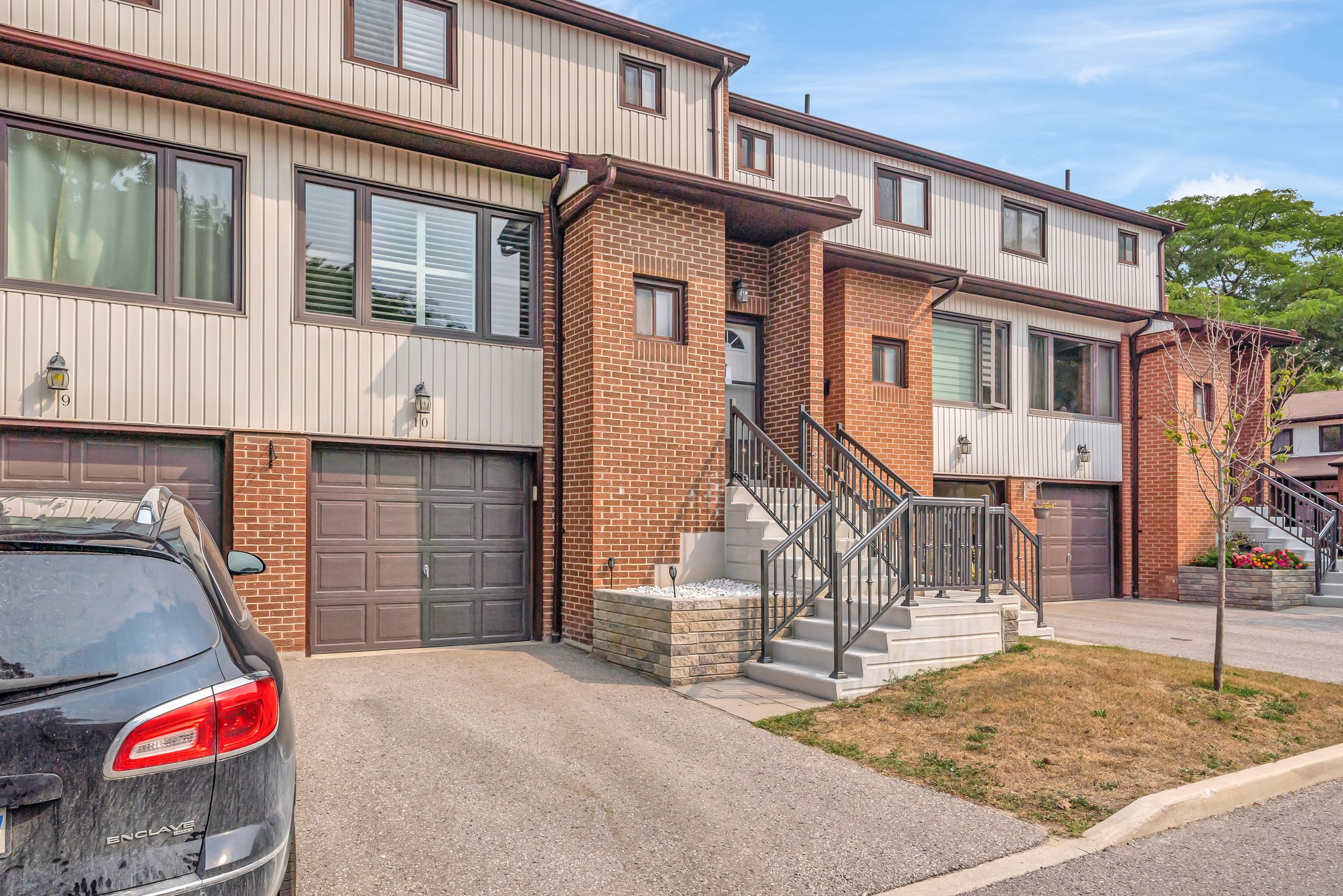 Daylight exterior of a multi-level townhouse with garage and front steps at Unit 10 – 765 Oklahoma Dr. in Pickering, Ontario.
