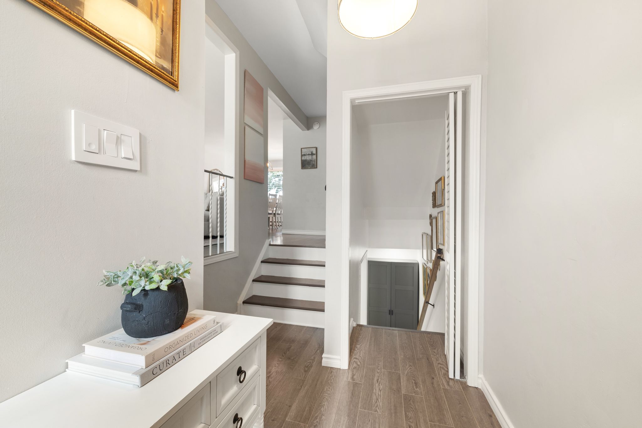Mid-level stair landing with view of foyer and upper dining area, styled with curated decor and natural wood flooring