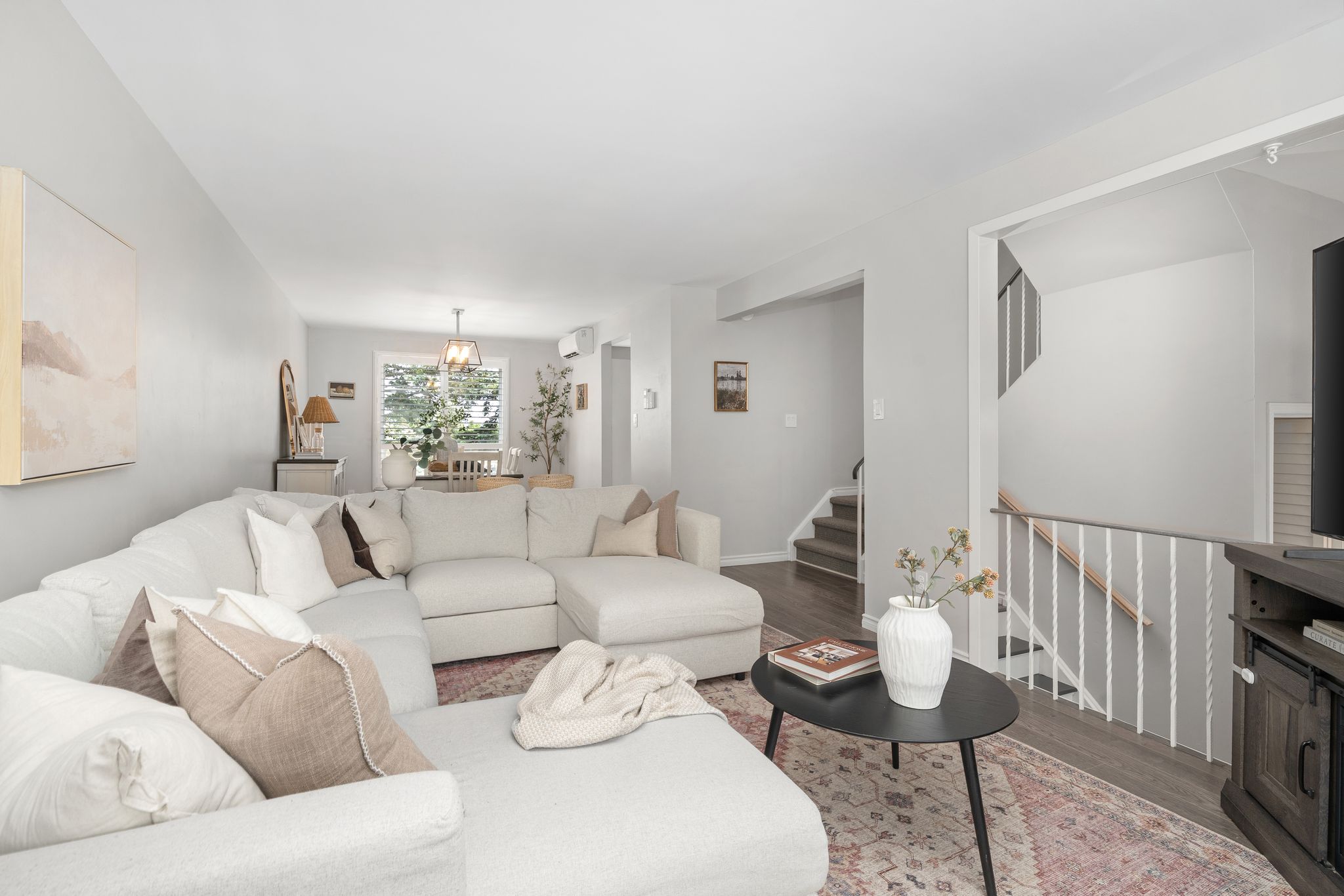 Open-concept living and dining space with soft neutral furnishings and contemporary lighting