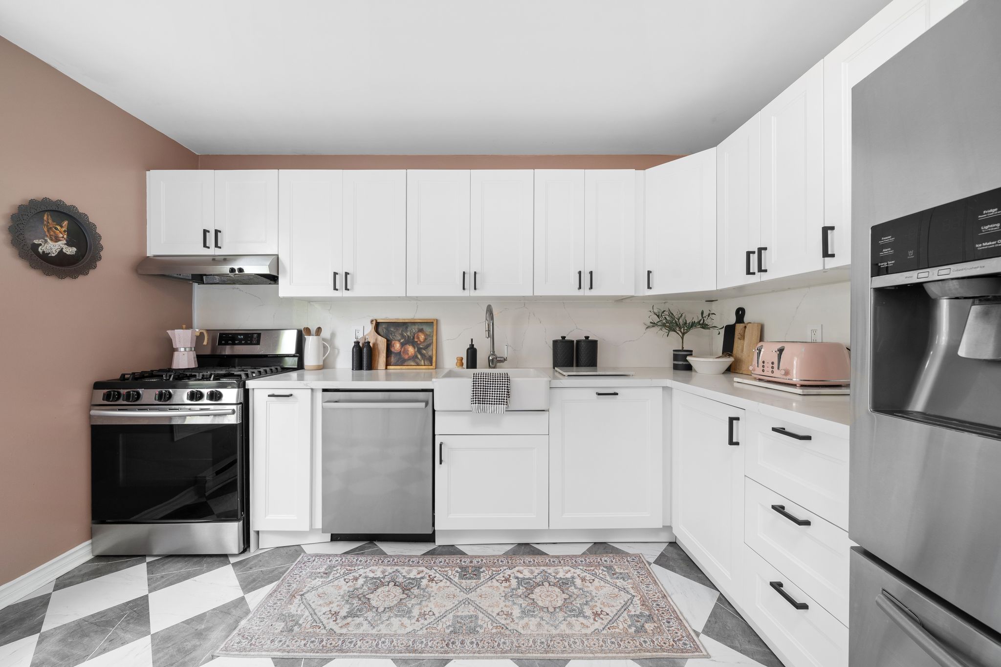 Renovated kitchen with white shaker cabinets, quartz counters, gas stove, and stainless steel appliances.