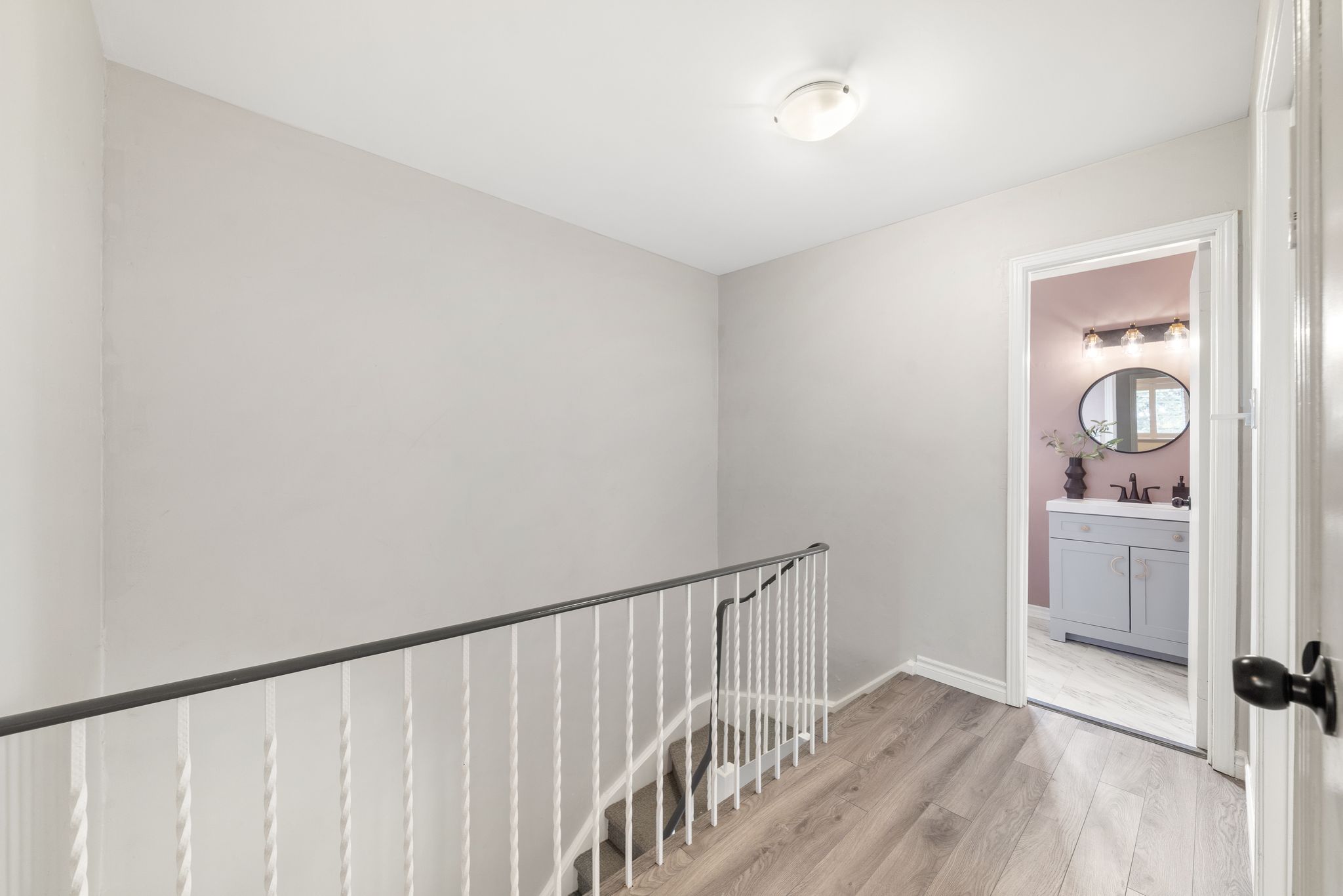 Upper staircase landing with wood-look floors, mid-century accents, and views into multiple levels