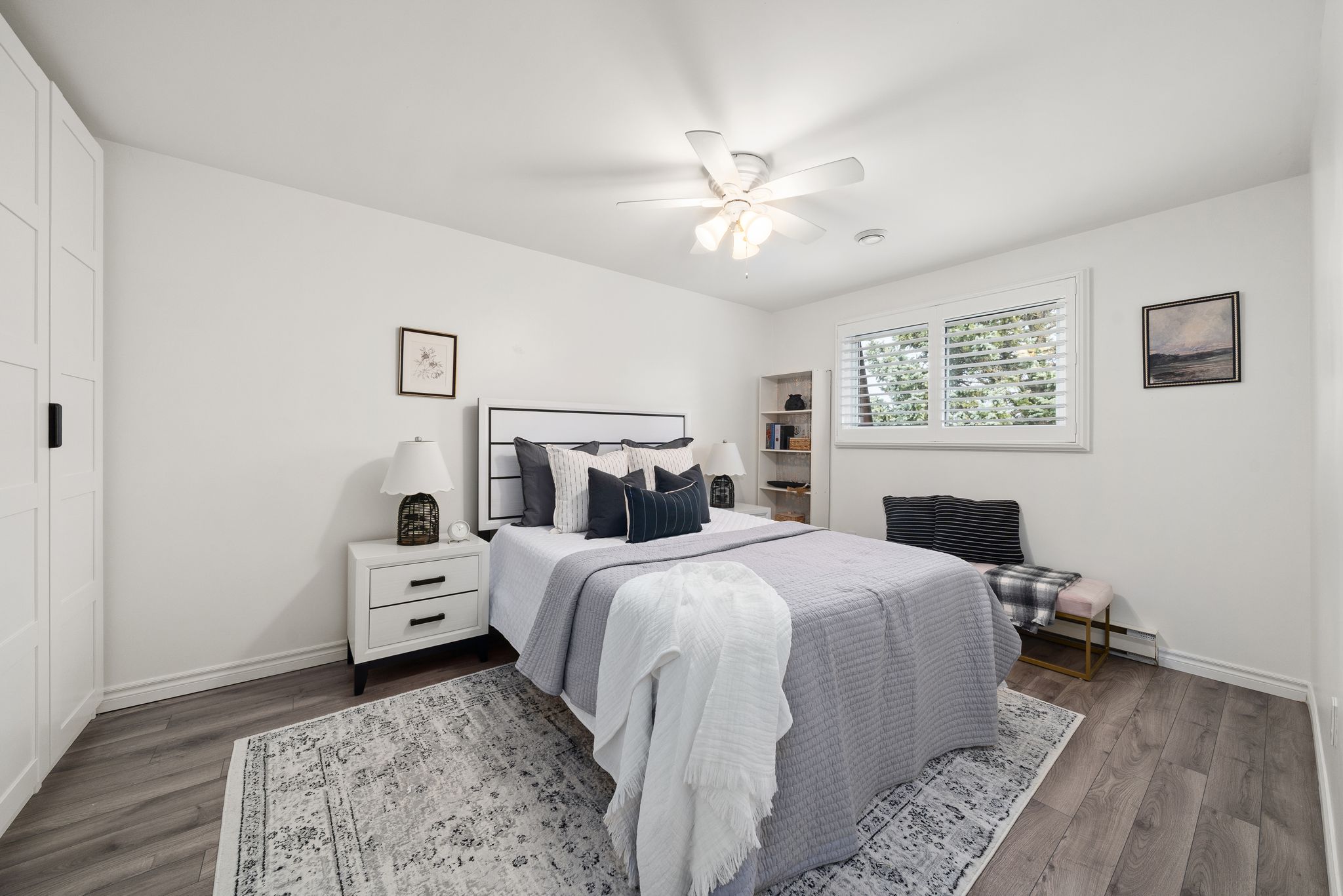 Bright and spacious primary bedroom with laminate floors, large window, and modern furnishings
