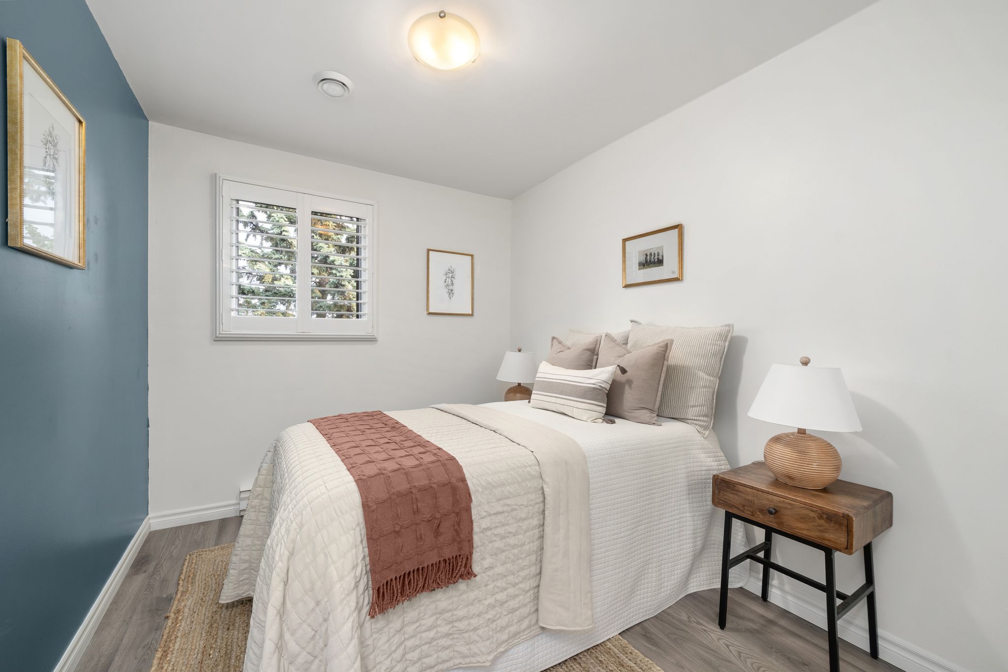 Cozy second bedroom with blue accent wall and neutral bedding