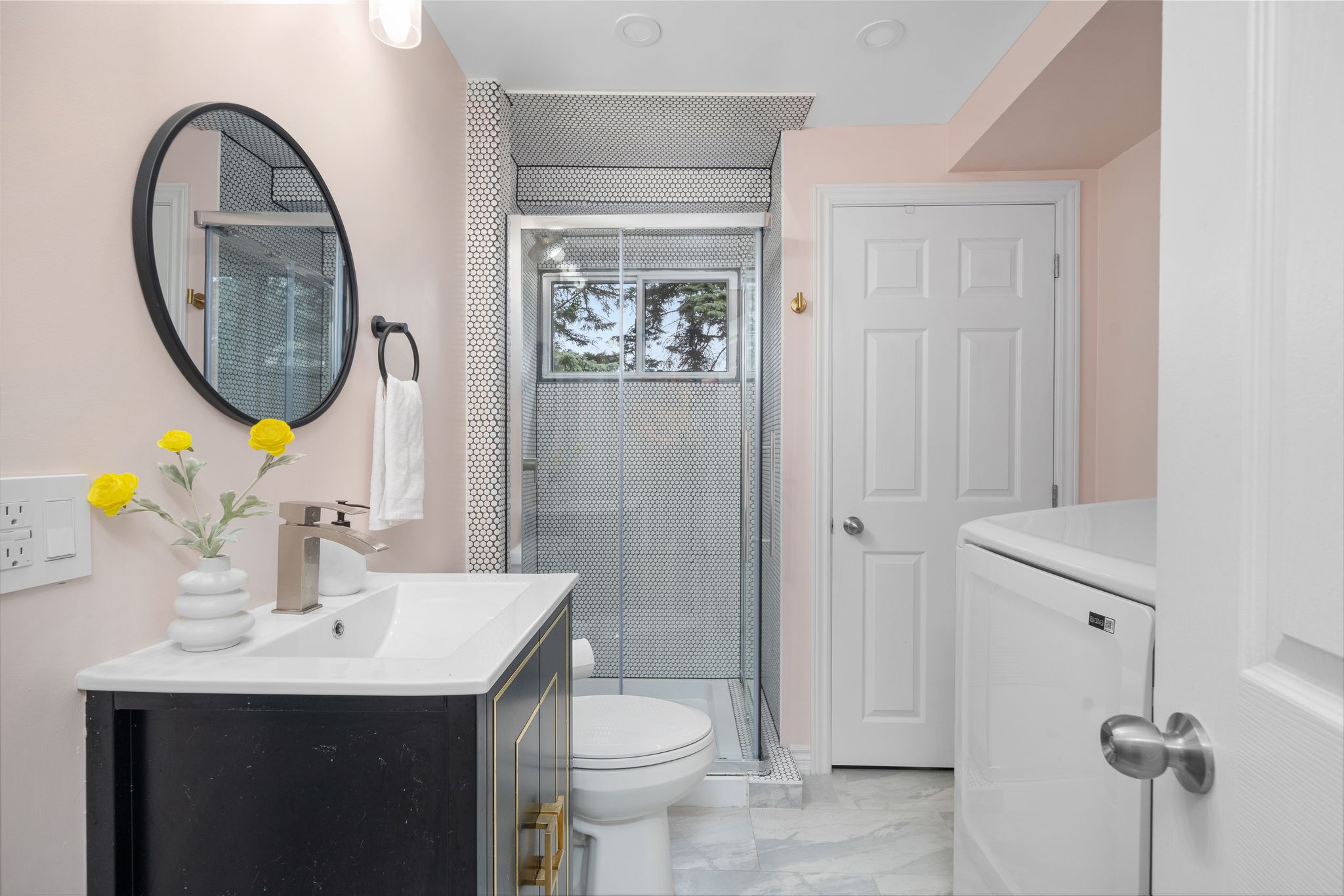 Stylish lower-level bathroom with glass shower, marble tile flooring, and in-unit laundry.