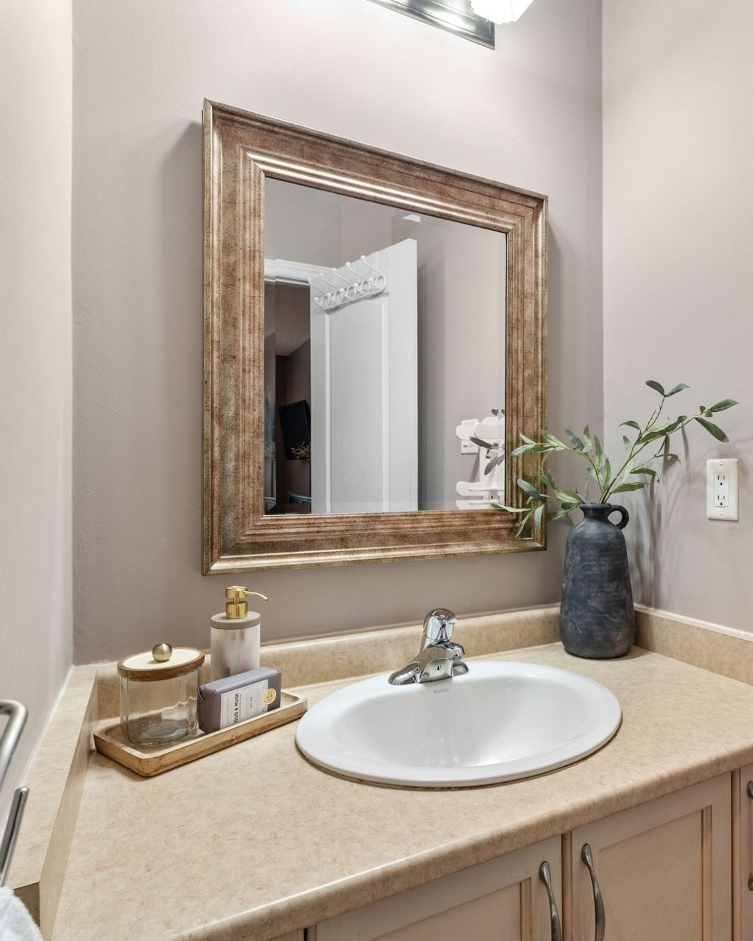 Ensuite bathroom vanity with framed mirror, neutral countertop, and decorative accents.