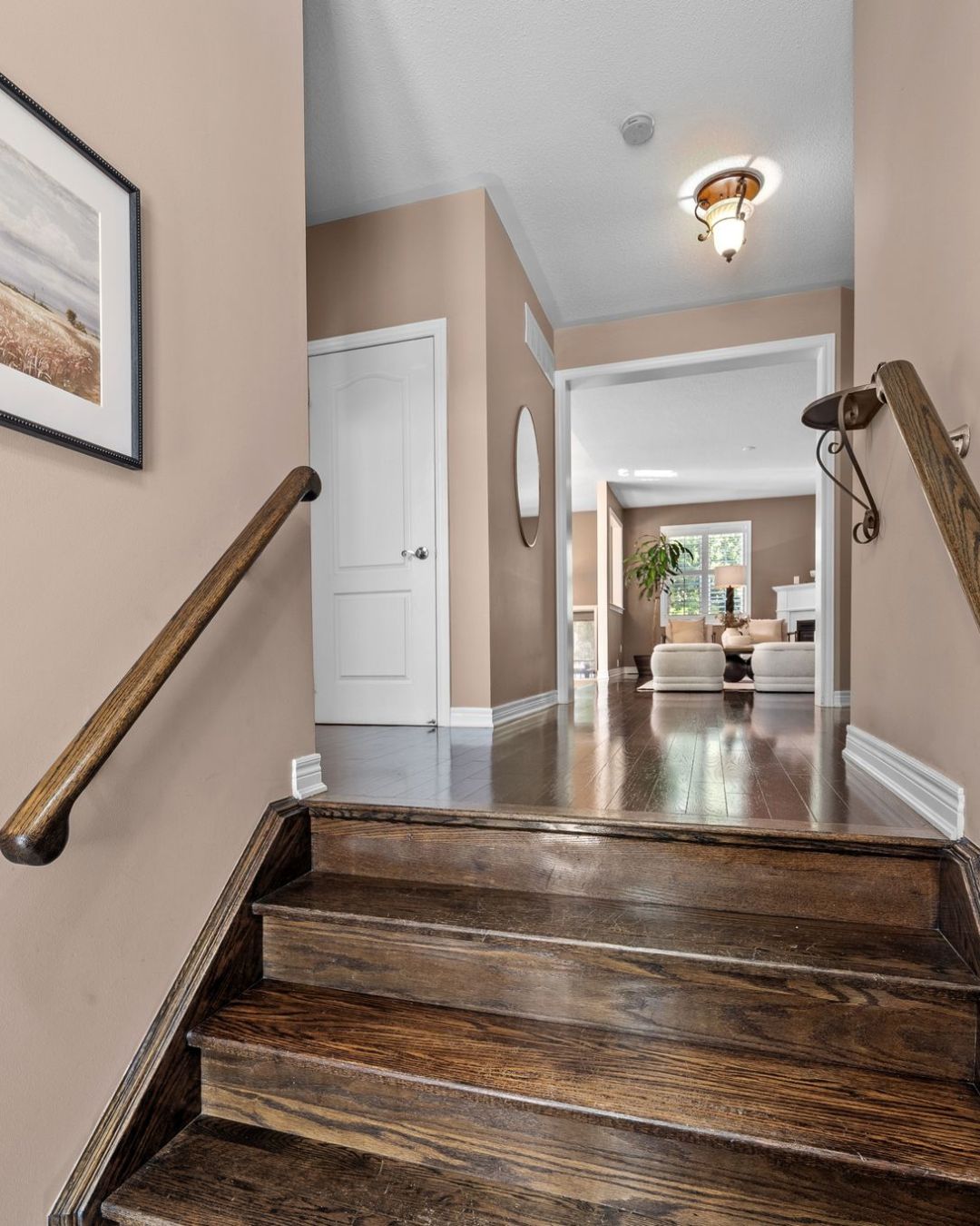 Entryway at 14 Sleepy Hollow Place in Whitby, showing wood staircase leading to the main level with hardwood floors and view into the living room.