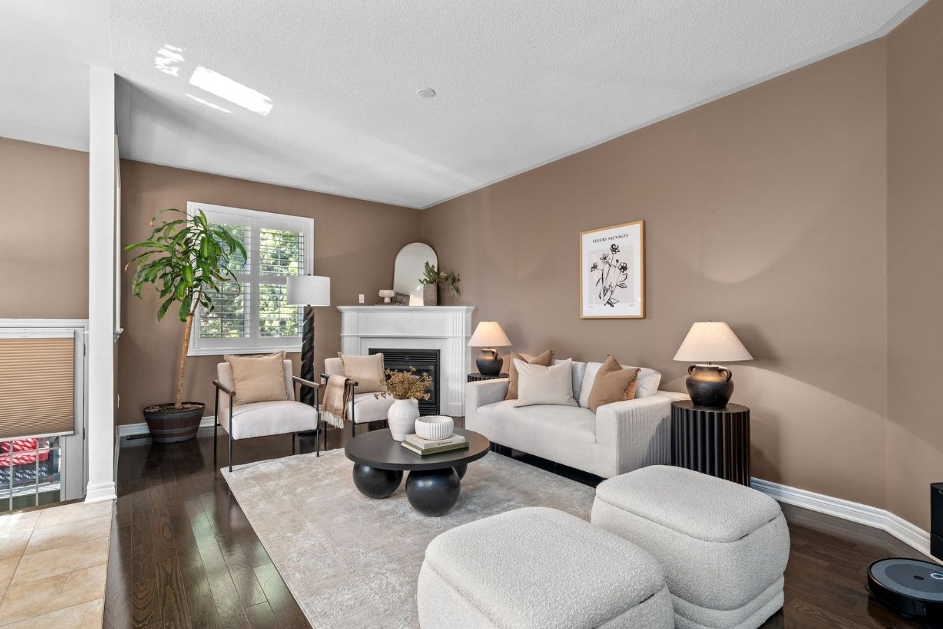 Living room at 14 Sleepy Hollow Place in Whitby with neutral sofa, accent chairs, gas fireplace, large window with shutters, and hardwood floors.