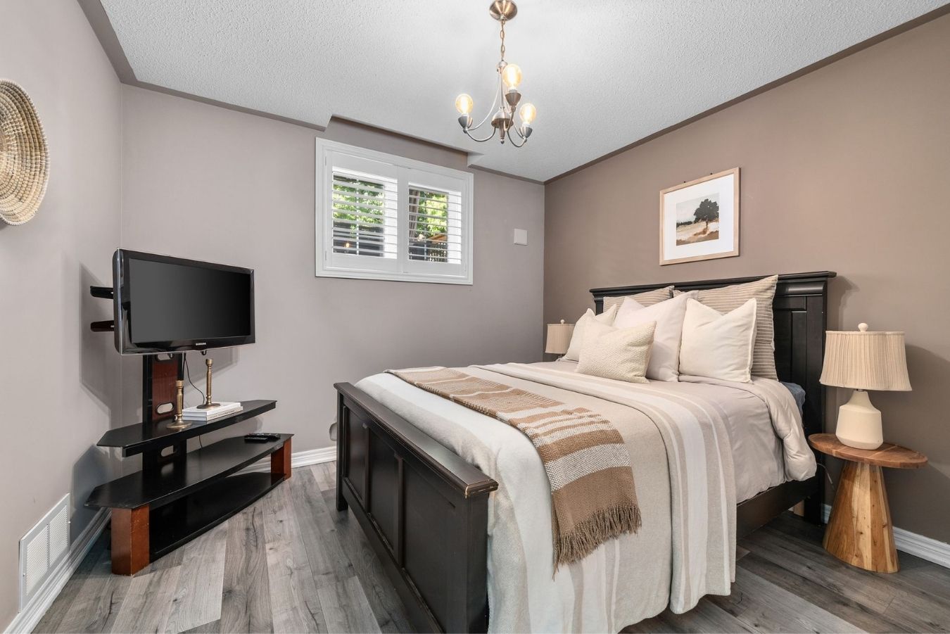 Third bedroom featuring a large window with California shutters, hardwood-style flooring, and warm-toned décor.