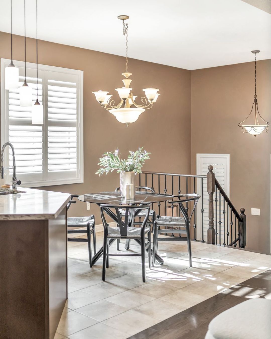 Bright breakfast area at 14 Sleepy Hollow Place in Whitby, featuring a glass table with four chairs, chandelier lighting, tile flooring, and natural light from a window with California shutters.
