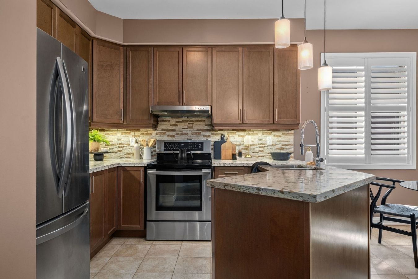 Modern kitchen at 14 Sleepy Hollow Place in Whitby, featuring maple cabinets, granite counters, tile backsplash, stainless steel appliances, center island with sink, and pendant lighting.