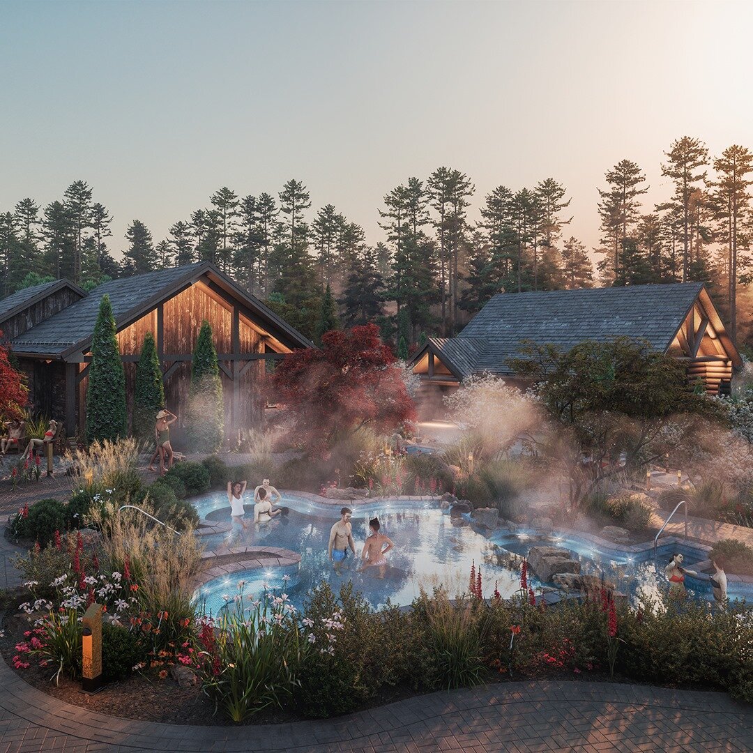 Outdoor thermal pools at Thermëa Spa Village in Whitby, Ontario, surrounded by landscaped gardens, steam, and rustic wood cabins at sunset.
