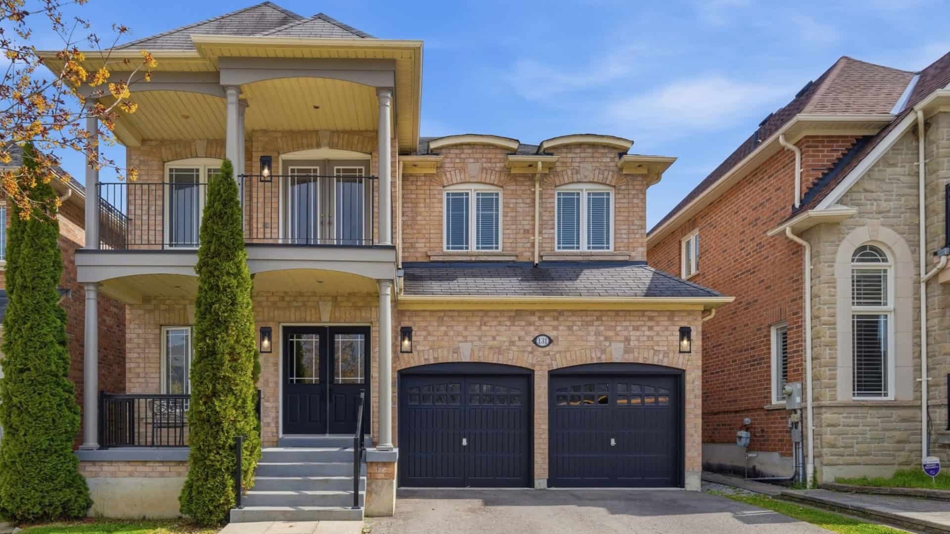 Exterior front view of 131 Rushworth Drive in Ajax with brick façade, covered porch, balcony, and double garage