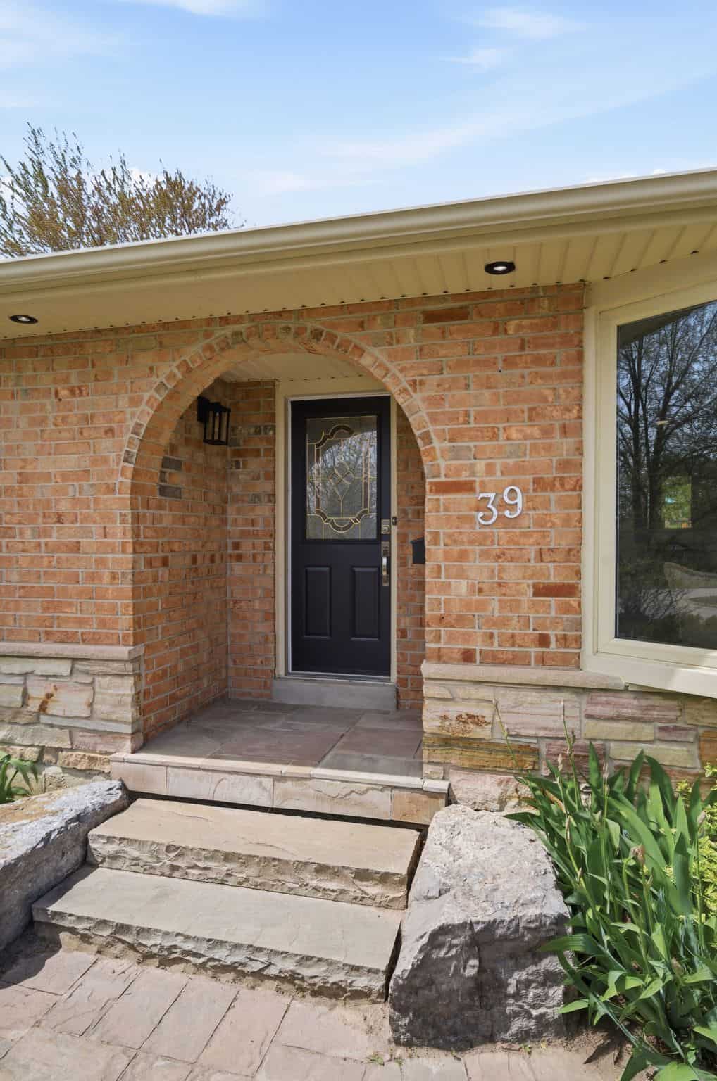 Arched brick front entry at 39 Anstead Crescent in Ajax with a black front door and stone steps.