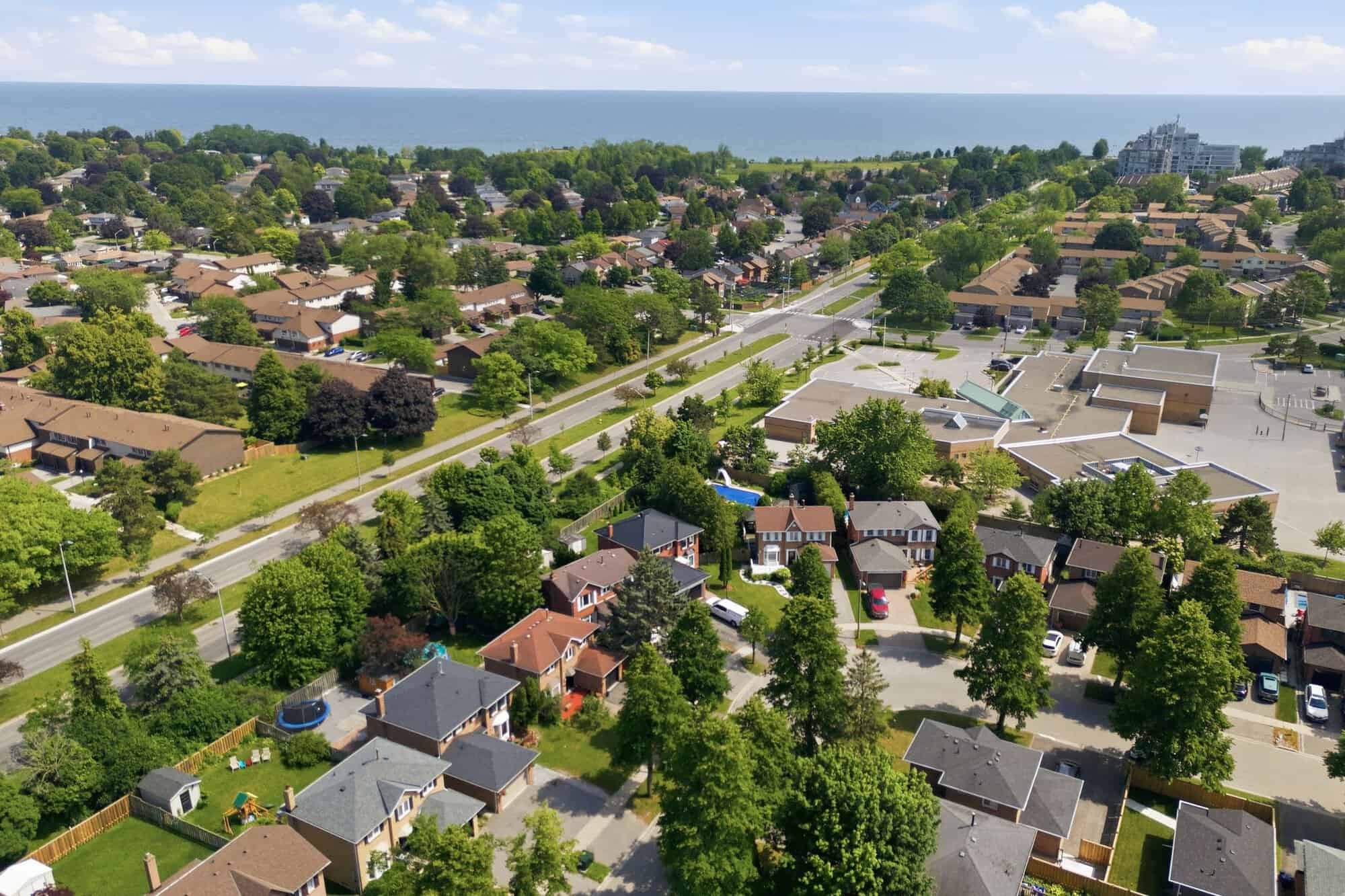 Aerial view of the neighbourhood surrounding 13 Flowers Crescent in Ajax, with nearby homes, green space, local streets, and Lake Ontario in the distance.