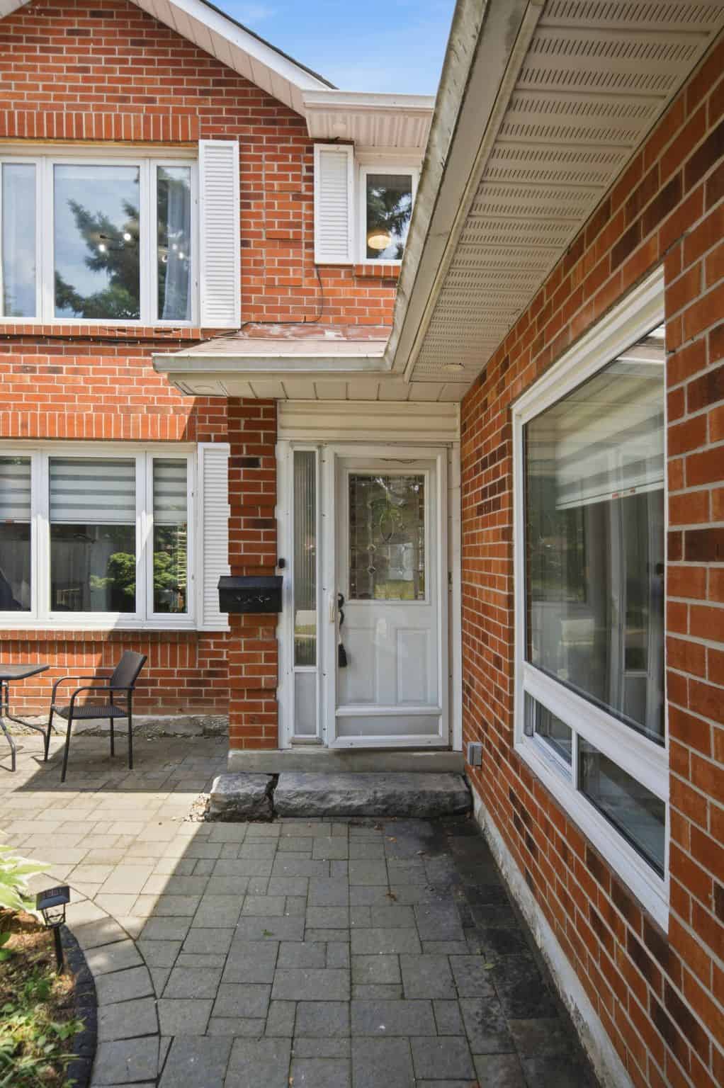Paved walkway leading to the front entrance of 13 Flowers Crescent in Ajax, framed by red-brick exterior walls and large windows.