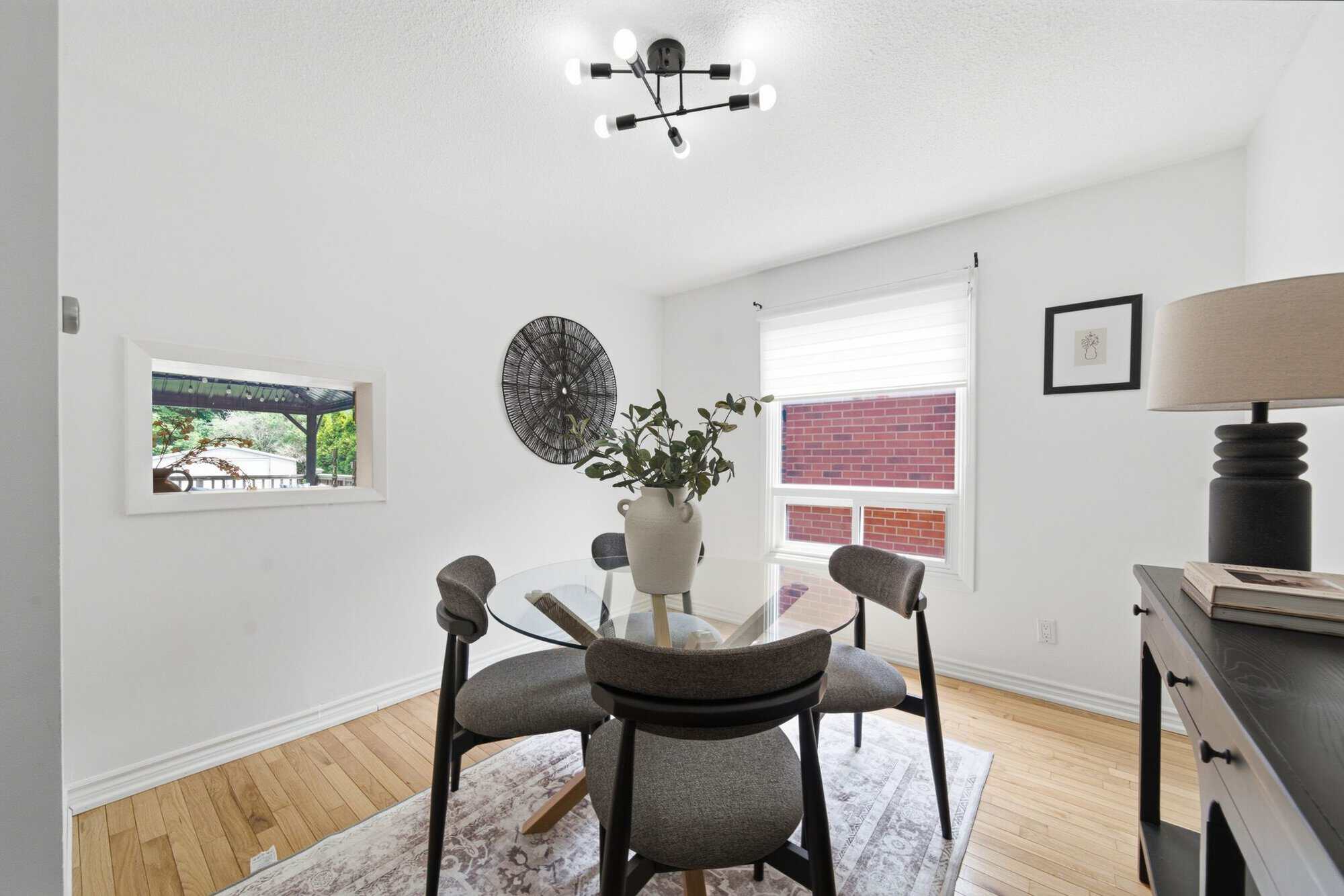 Dining room at 13 Flowers Crescent in Ajax with a glass table, four chairs, hardwood floors and a pass-through opening to the backyard.