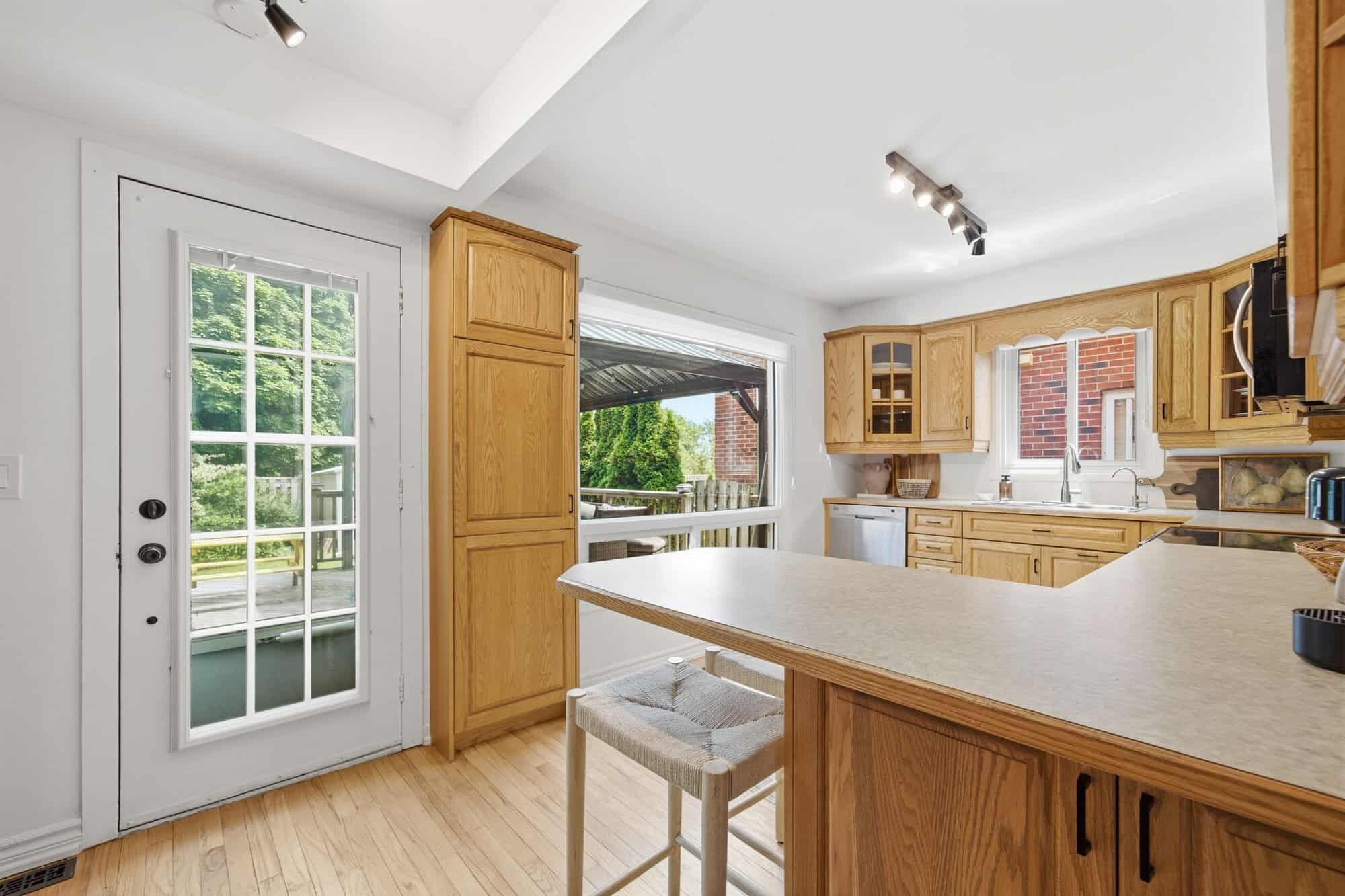 Kitchen at 13 Flowers Crescent in Ajax with oak cabinetry, breakfast bar, hardwood floors and a glass door to the backyard deck.