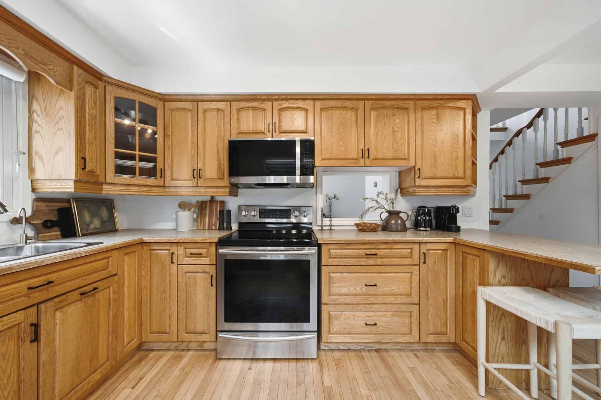 Kitchen at 13 Flowers Crescent in Ajax with oak cabinets, stainless steel stove, pass-through opening and breakfast seating.
