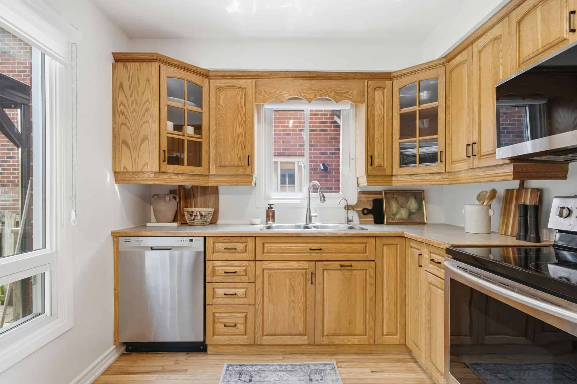 Kitchen sink area at 13 Flowers Crescent in Ajax with oak cabinets, stainless steel dishwasher and windows above the counter.