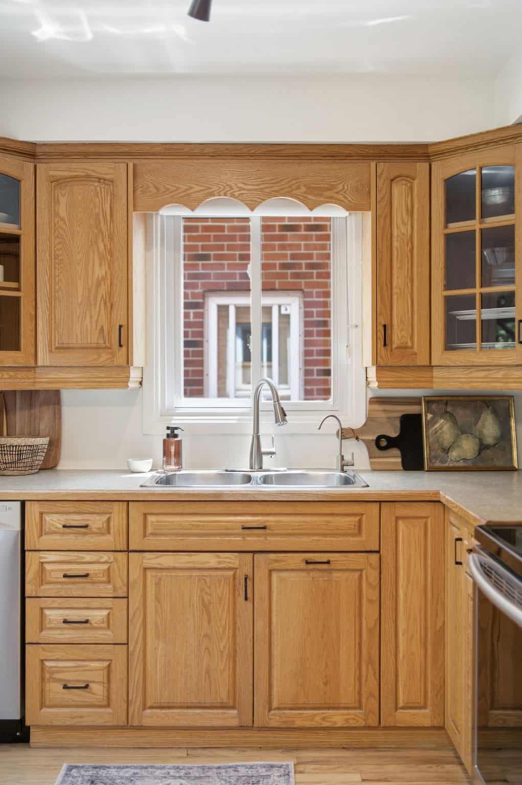 Kitchen sink at 13 Flowers Crescent in Ajax with oak cabinetry, a double stainless steel sink and a window above the counter.