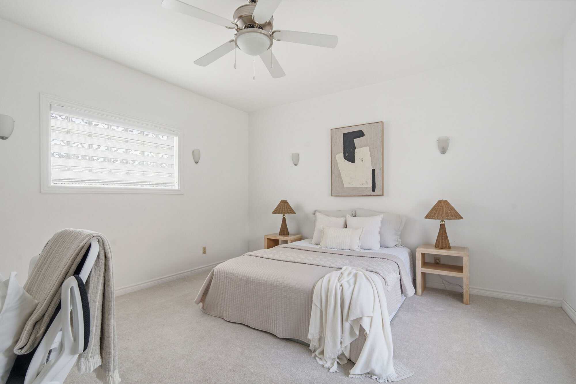 Spacious main floor bedroom at 13 Flowers Crescent in Ajax with neutral bedding, two wood nightstands, woven lamps and a ceiling fan.