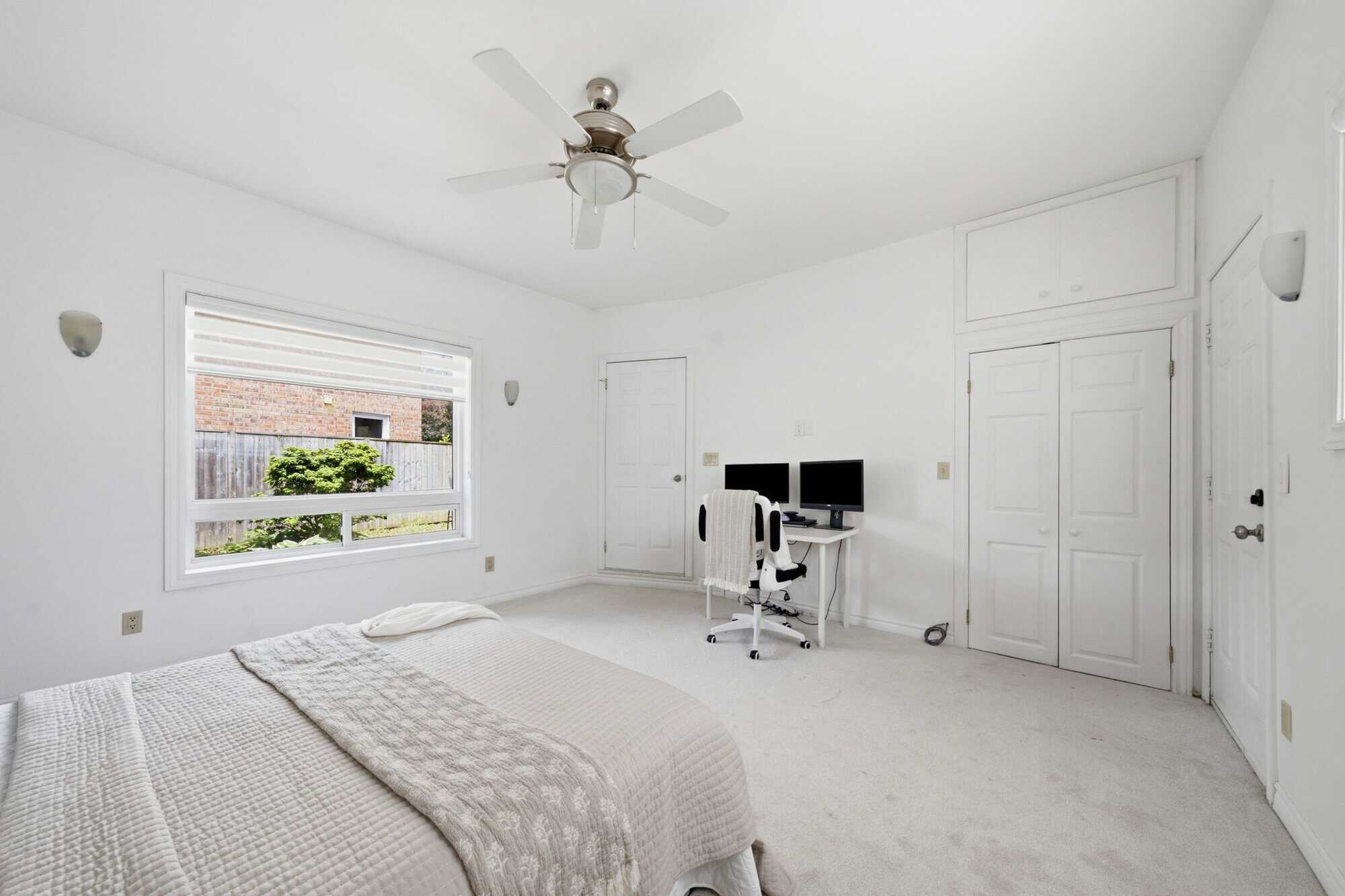 Bedroom at 13 Flowers Crescent in Ajax showing a large window, built-in storage, workspace and exterior door.