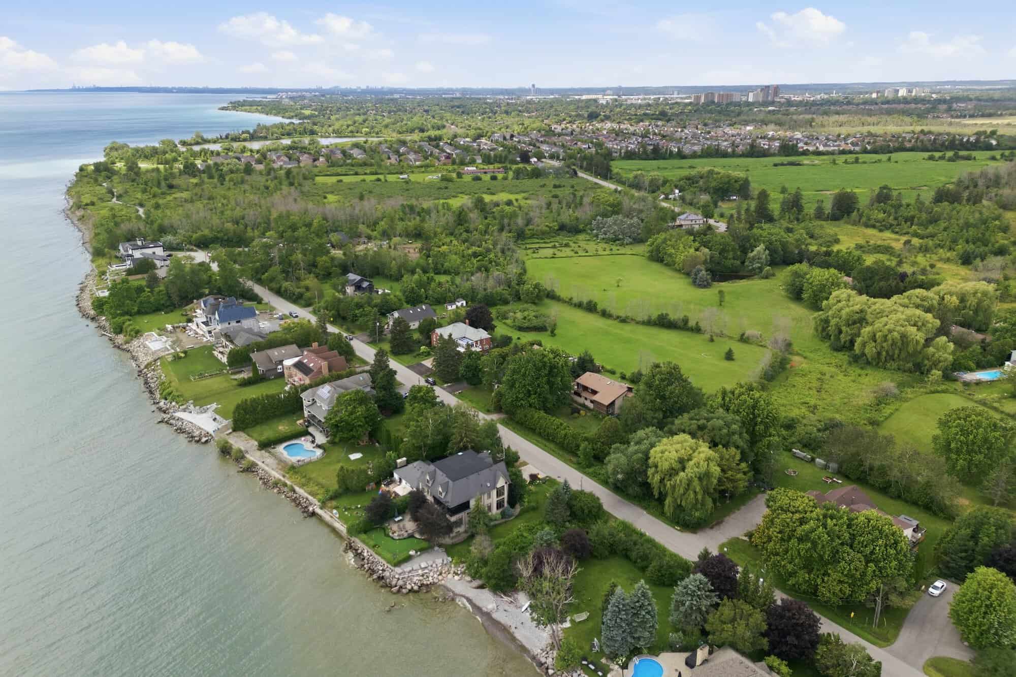 High-altitude aerial view of South Ajax's Lake Ontario shoreline, showcasing estate homes, expansive green space, mature forest, and the surrounding Tribute Lakeside community.