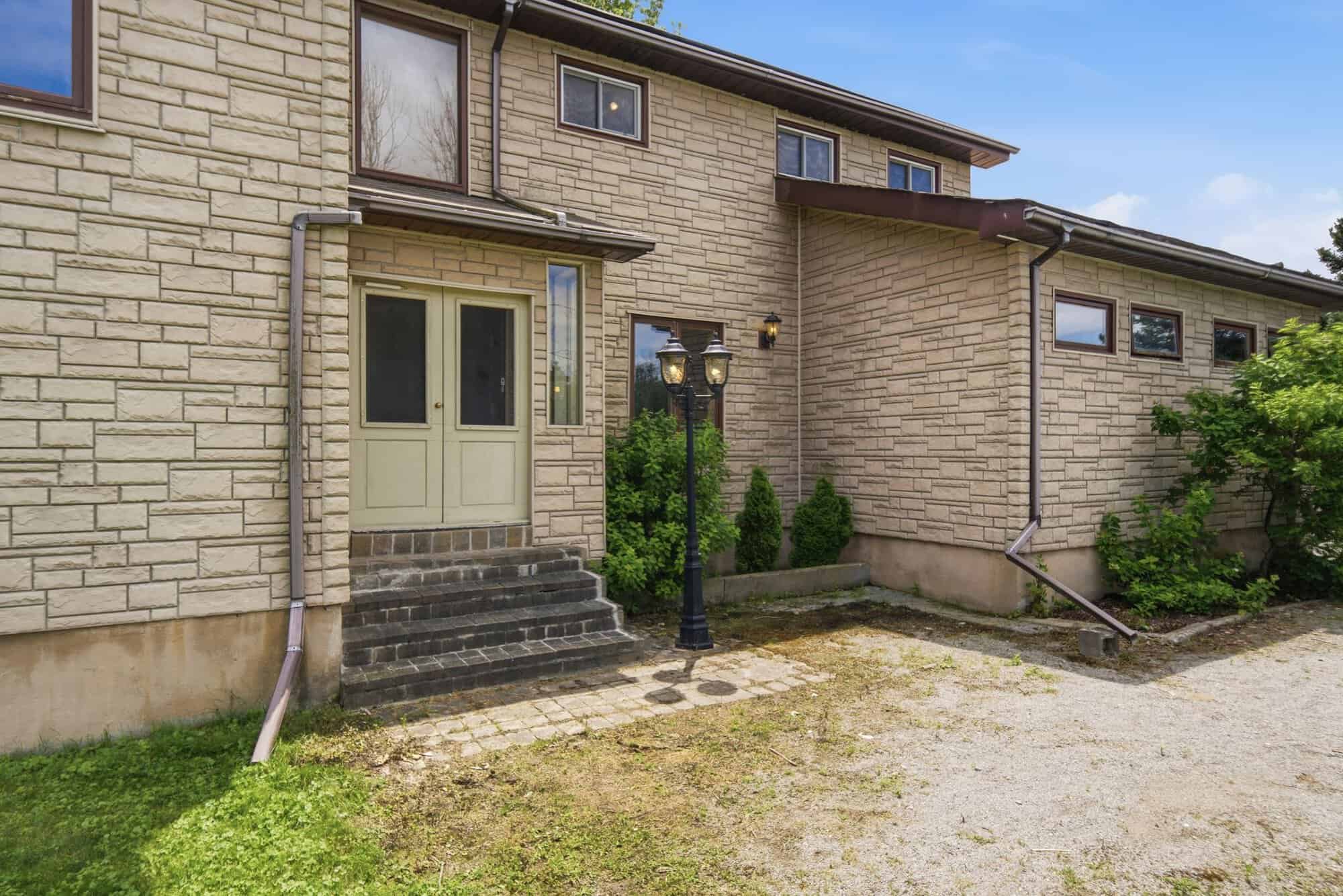 Stone-look front entrance with double doors, cobblestone walkway, and classic lamp post welcoming guests to the home.