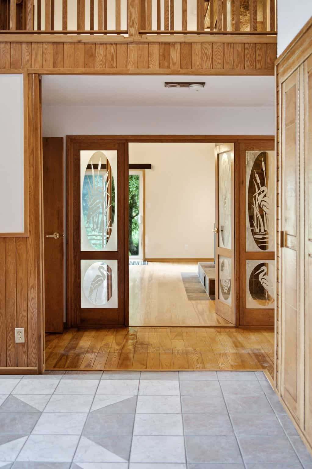 Spacious great room with vaulted ceilings, hardwood floors, oversized windows, and a dramatic floor-to-ceiling double-sided stone fireplace.