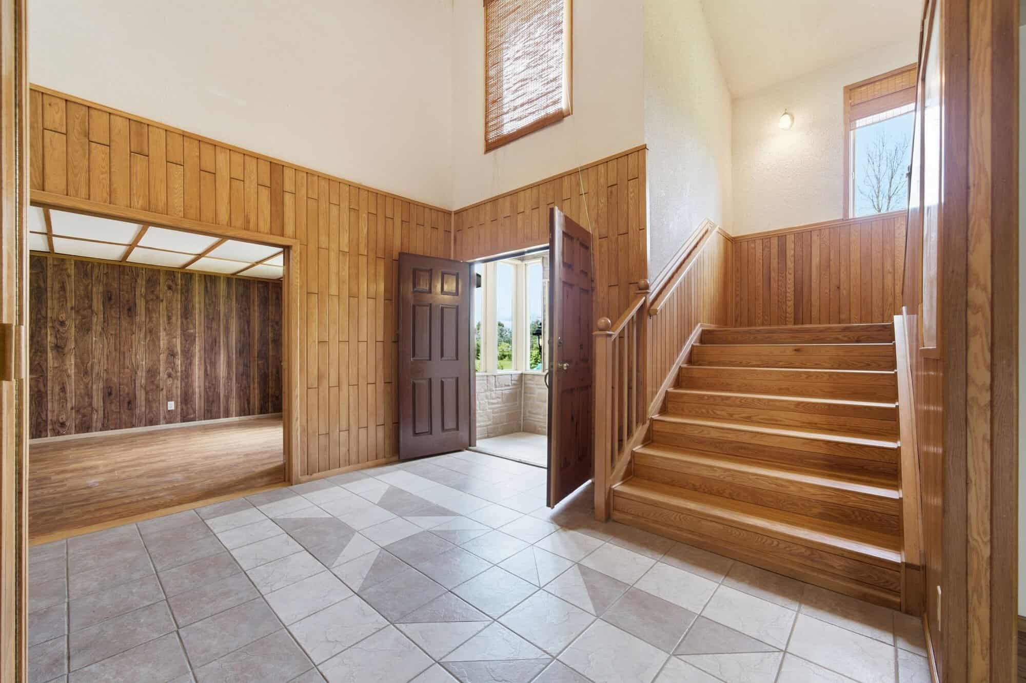 Grand two-storey foyer with open staircase, vaulted ceiling, upper gallery, tile flooring, and hardwood accents.