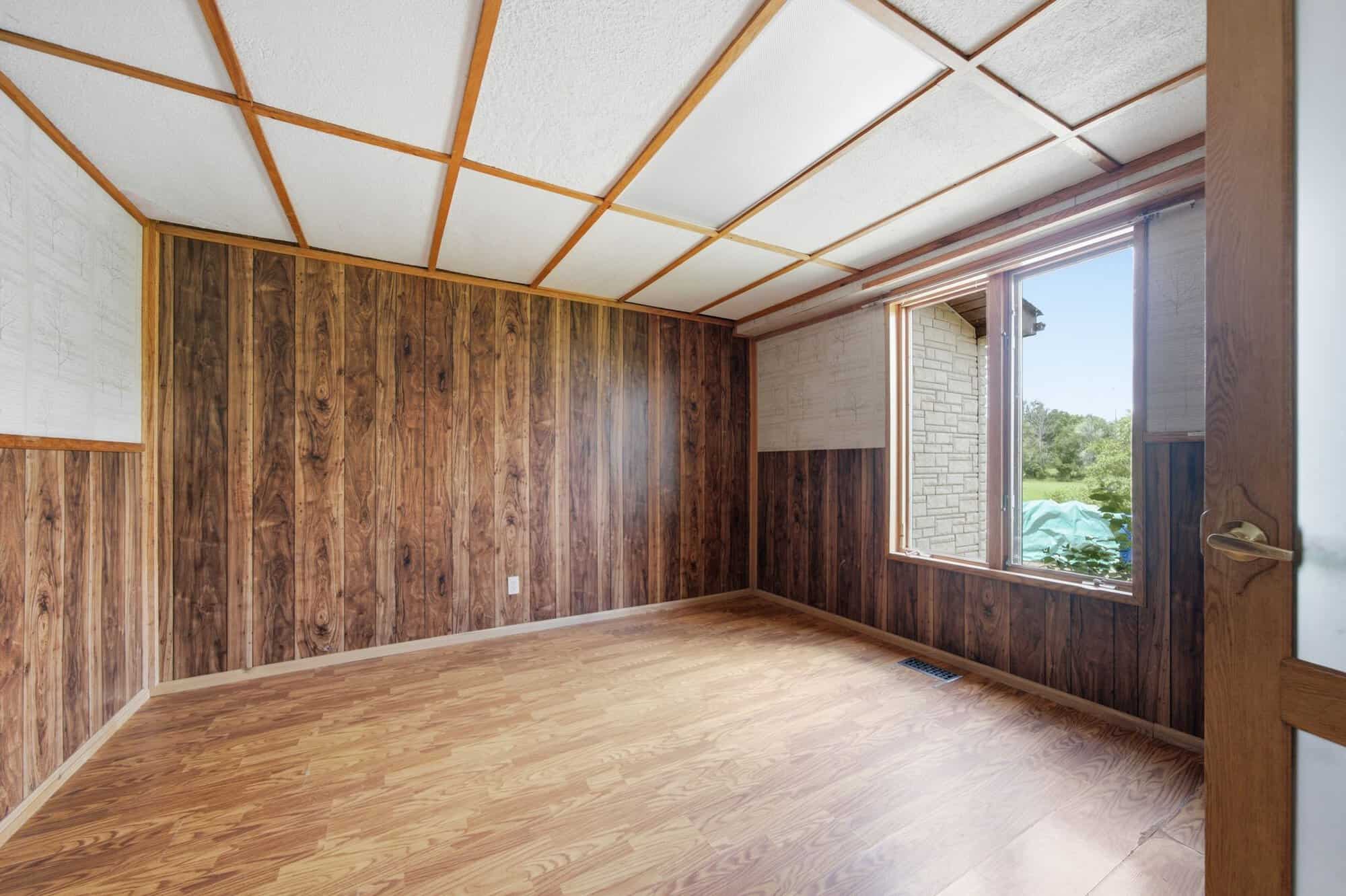 Main floor office with large picture window, wood-accent walls, and hardwood flooring.