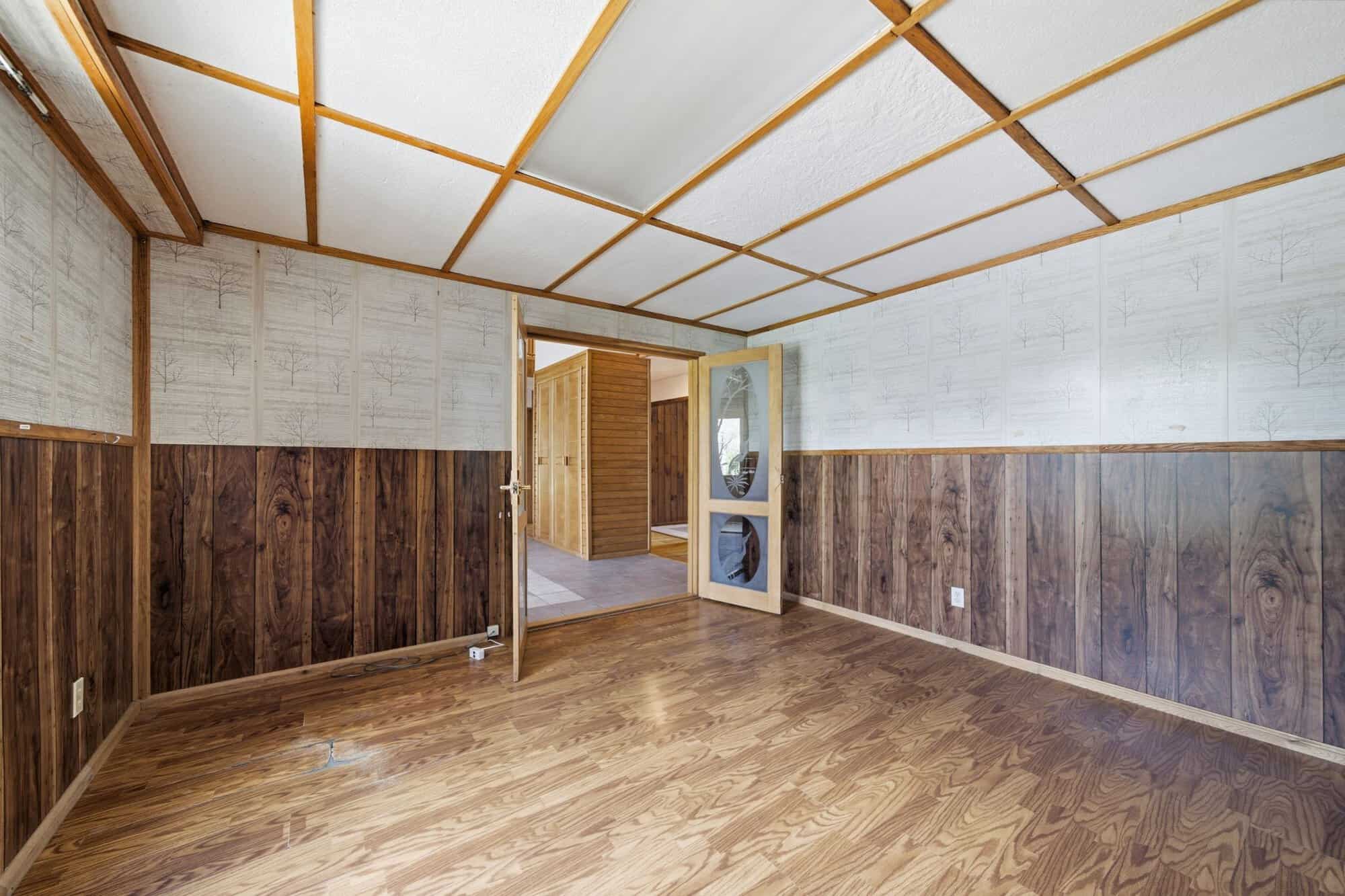 Main floor office with hardwood flooring, wood-accent walls, and decorative etched glass door.