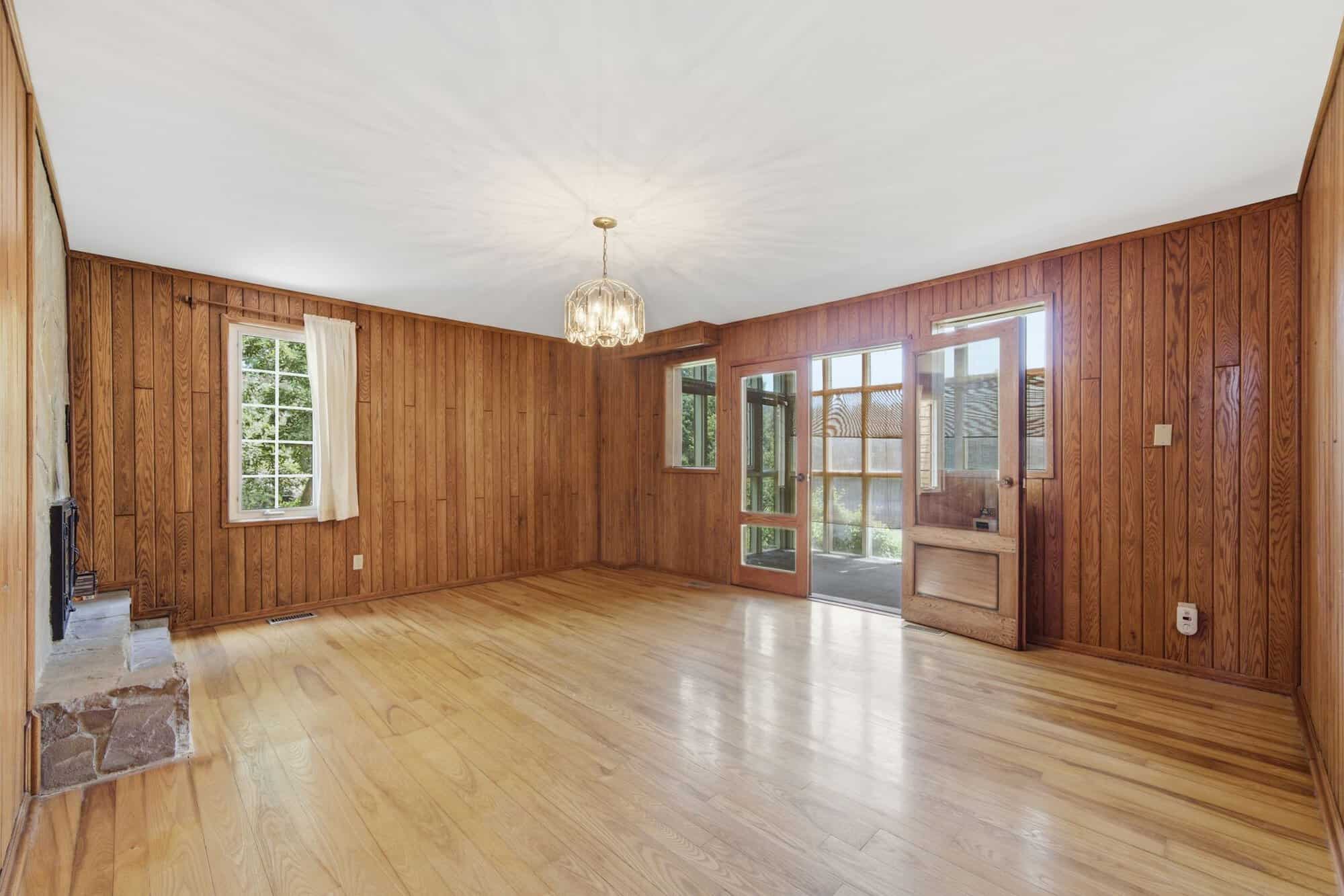 Dining room with hardwood floors, wood paneling, and a shared double-sided stone fireplace connecting to the great room.