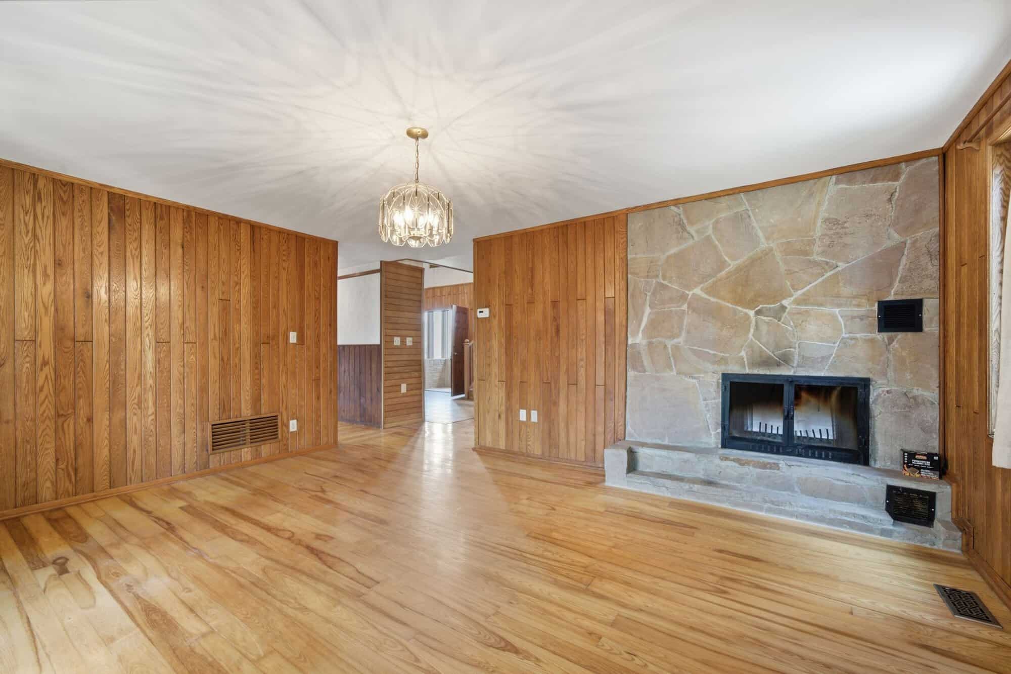 Dining room with hardwood floors, wood paneling, and a shared double-sided stone fireplace connecting to the great room.