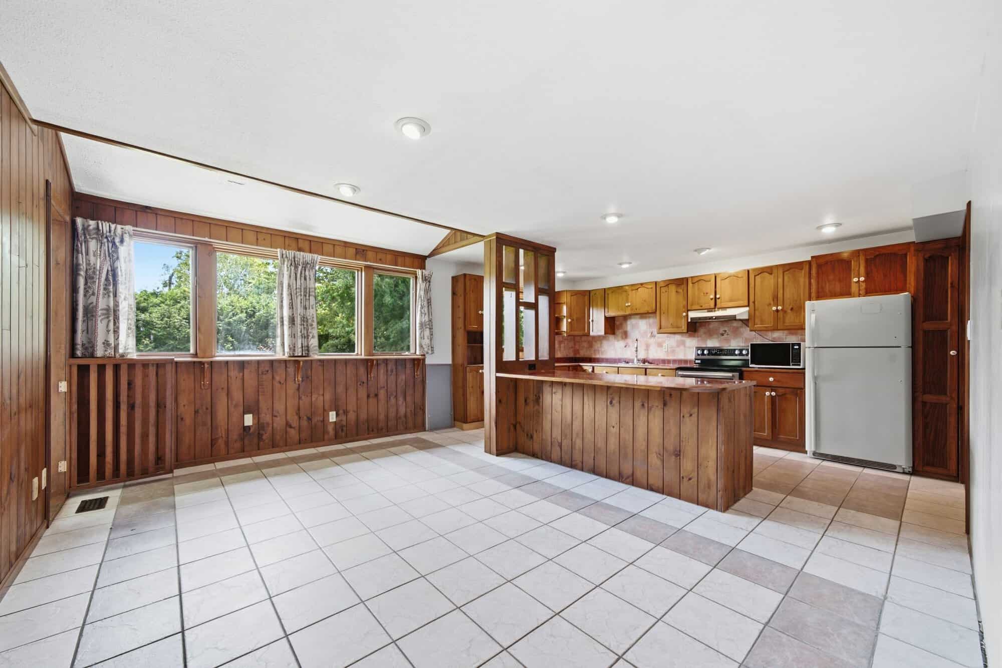 Bright breakfast area with tiled floor, wood accent wall, and direct access to the conservatory.