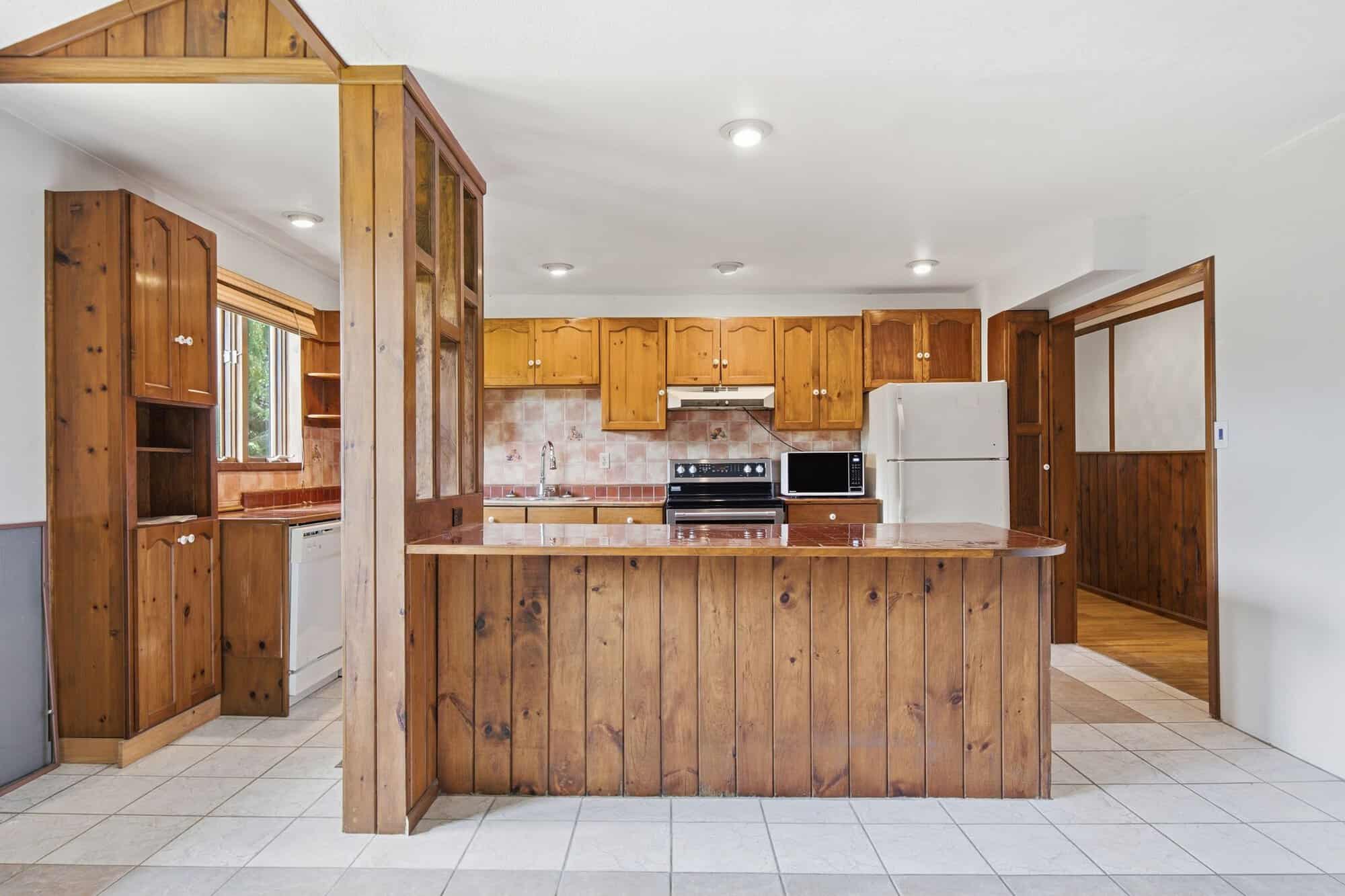 Large eat-in kitchen with extensive wood cabinetry, peninsula seating, tiled flooring, and breakfast area.