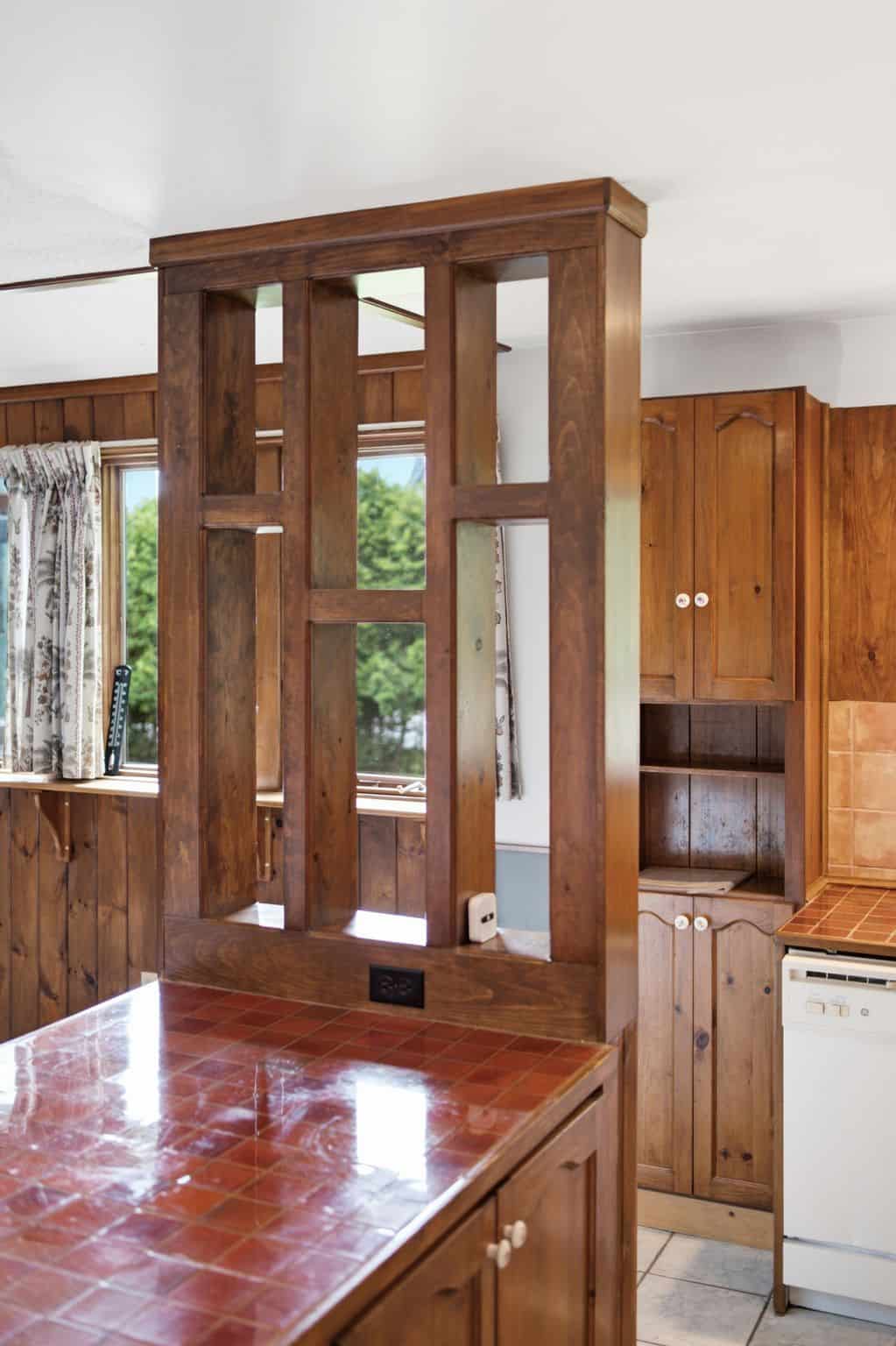 Custom wood kitchen peninsula with decorative divider and tiled countertop.