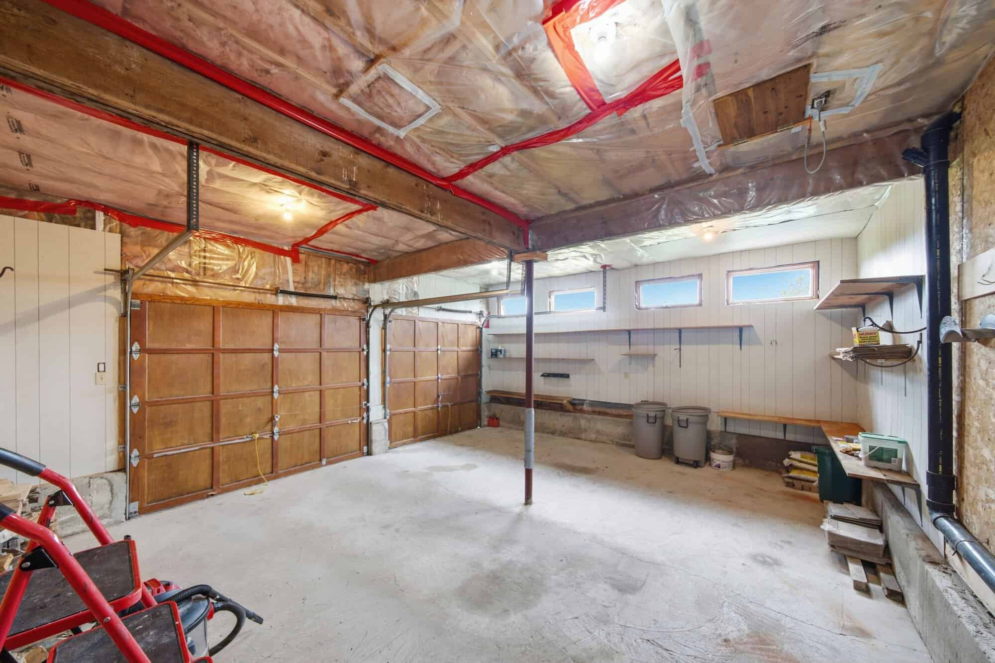 Oversized attached two-car garage with insulated overhead doors, workshop shelving, concrete floor, and abundant storage space.